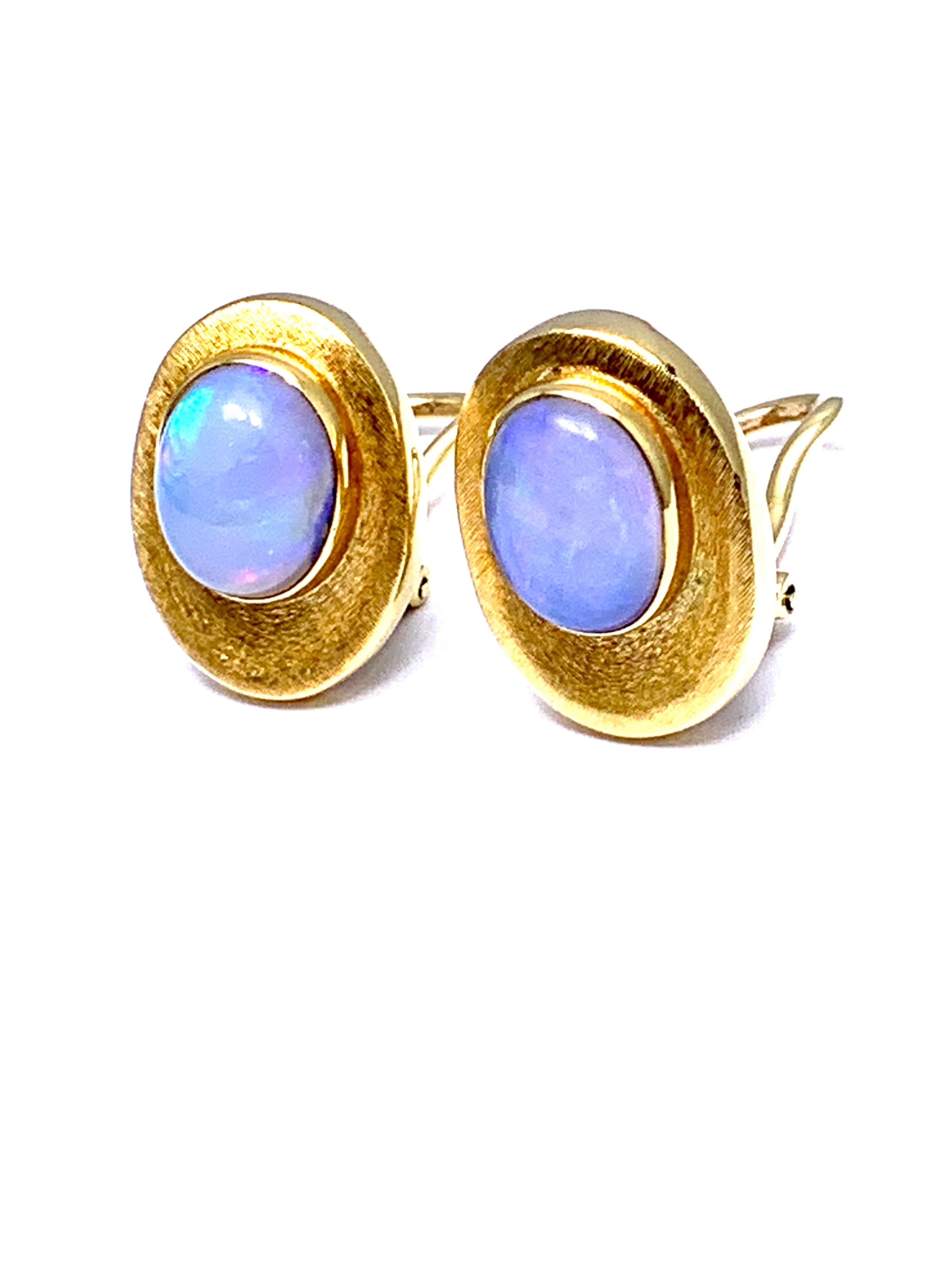 A wonderful pair of cabochon Opal clip earrings designed by Bruno Guidi.  The 3.65 carat opal display a bluish hue and have great play of color throughout.  They are bezel set in an 18k yellow gold oval frame with a brushed finish.  The earrings are
