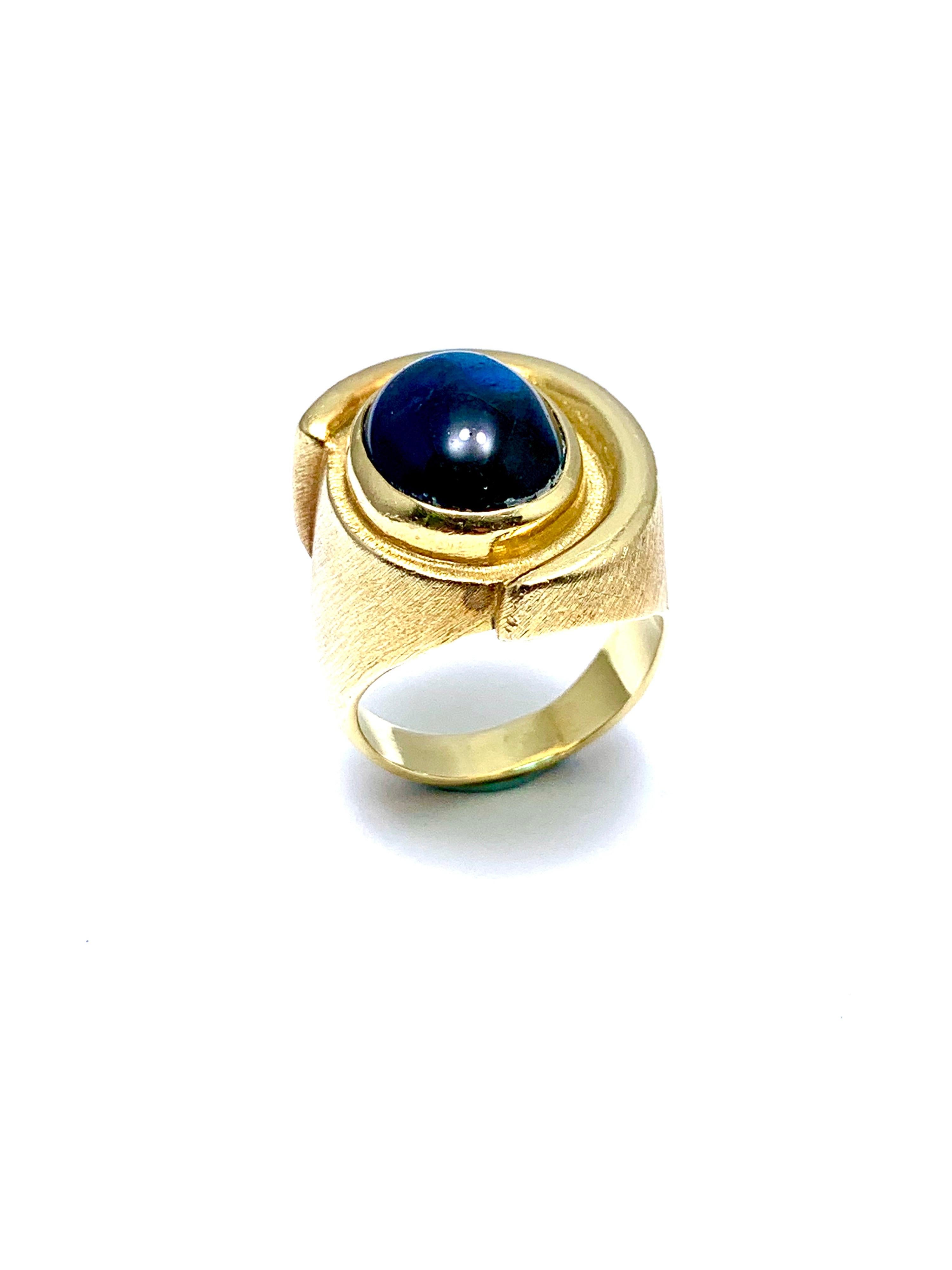 A gorgeous Indicolite Tourmaline fashion ring designed by Bruno Guidi.  The 6.43 cabochon Indicolite displays a lustrous teal color, bezel set in an 18 karat yellow gold abstarct design ring.  The inside shank is signed 