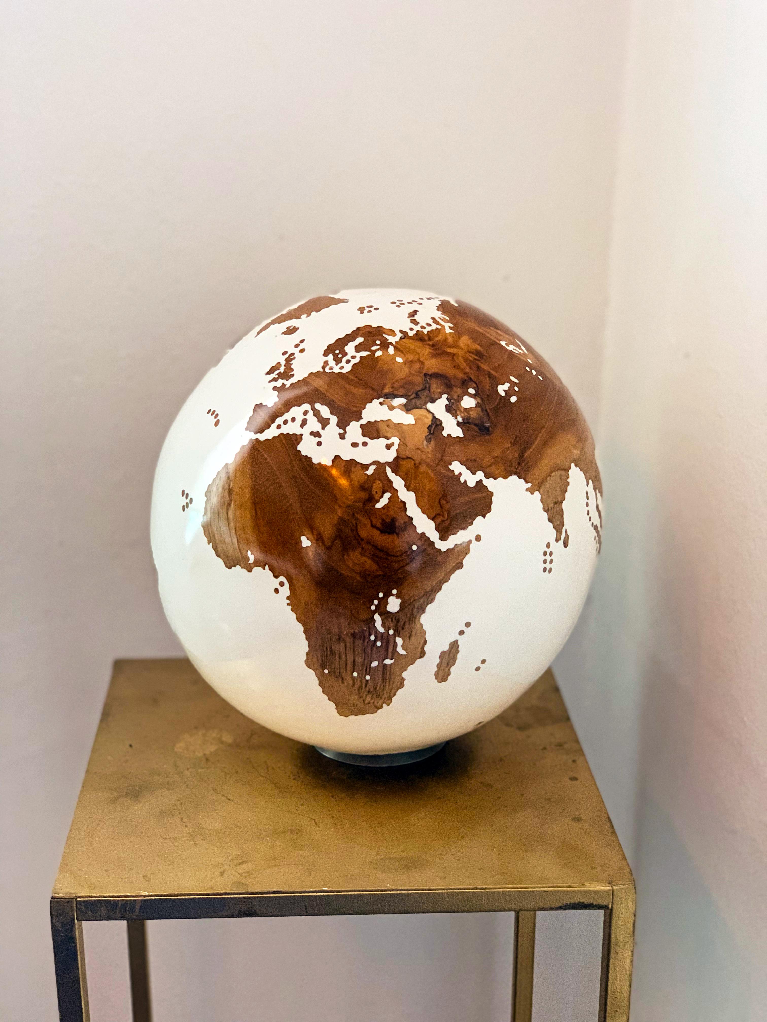 Original globe made out of teak wood, countries are carved out of the wood, then the water is finished in white.

As the shape of the wood, texture and color is unique, so is this elegant sculpture. Signed, dated and numbered.

Turns on base.