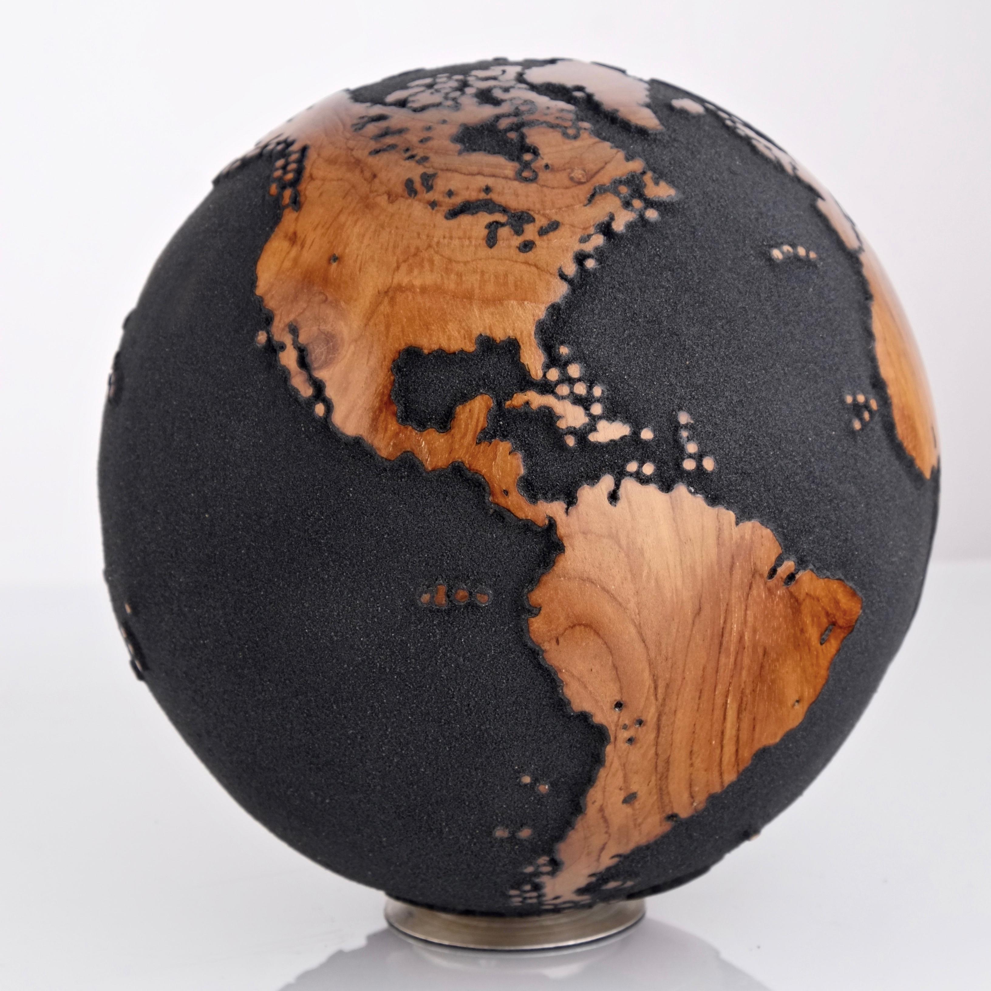 Teakwood and black lava sand make this beautiful turning globe a real stunning sculpture.
Made from a whole piece of wood the way the sculpture is shaped is defined by how the tree grew.
Sitting on a turning base the sculpture can spin silently