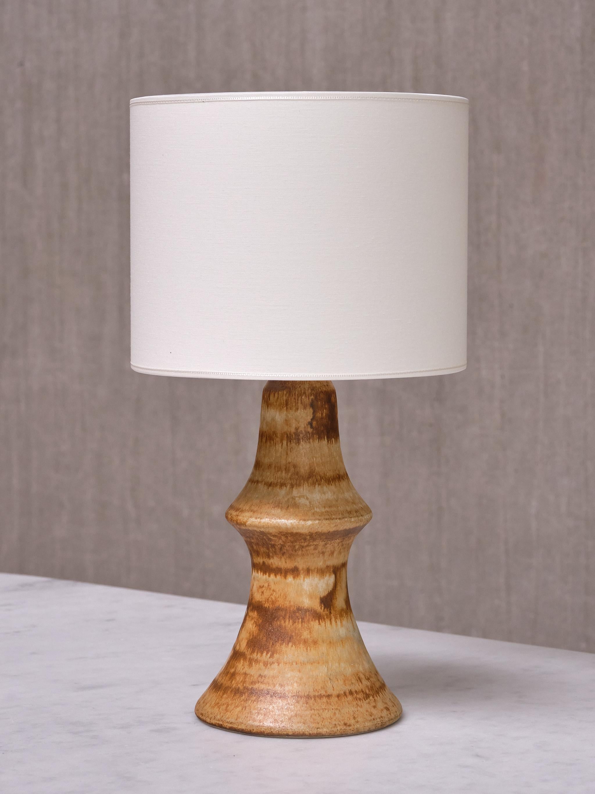 Cette lampe de table rare a été conçue par Bruno Karlsson et produite par Ego Stengods Ateljé en Suède dans les années 1960. La lampe est signée du nom du fabricant et des initiales du designer sur le dessous de la base. 

La base en céramique est