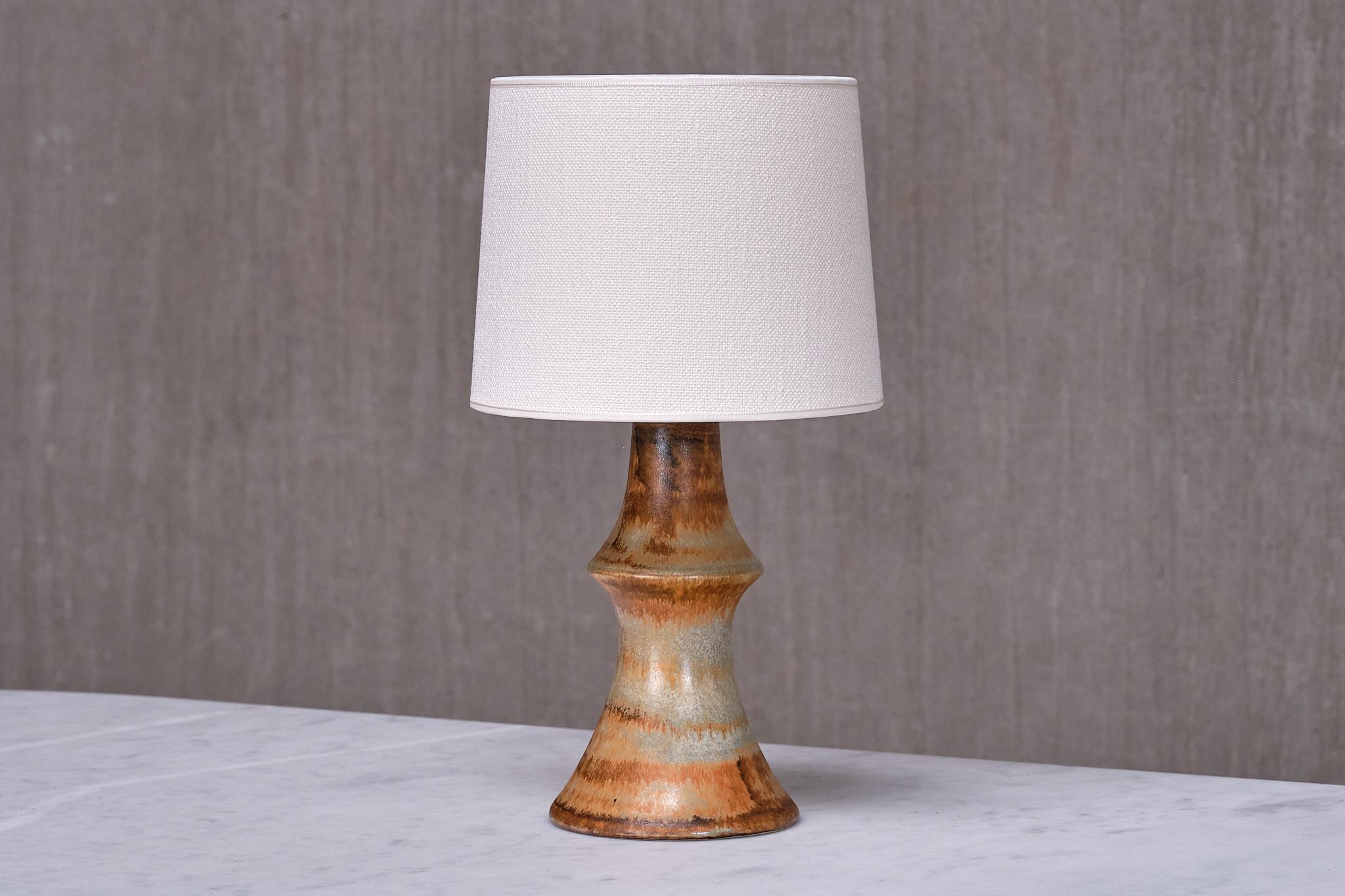 Cette lampe de table rare a été conçue par Bruno Karlsson et produite par Ego Stengods Ateljé en Suède dans les années 1960. La lampe est signée du nom du fabricant et des initiales du designer sur le dessous de la base.   

La base en céramique est