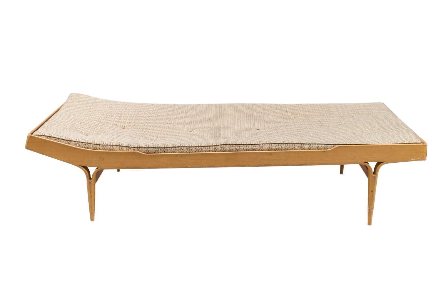 Bruno Mathsson, attributed to.

Berlin model of daybed in rectangular shaped stratified beech slightly elevated at the headboard. It stands on four fluted legs, which are fixed to the bed frame by two forks and linked each other by two