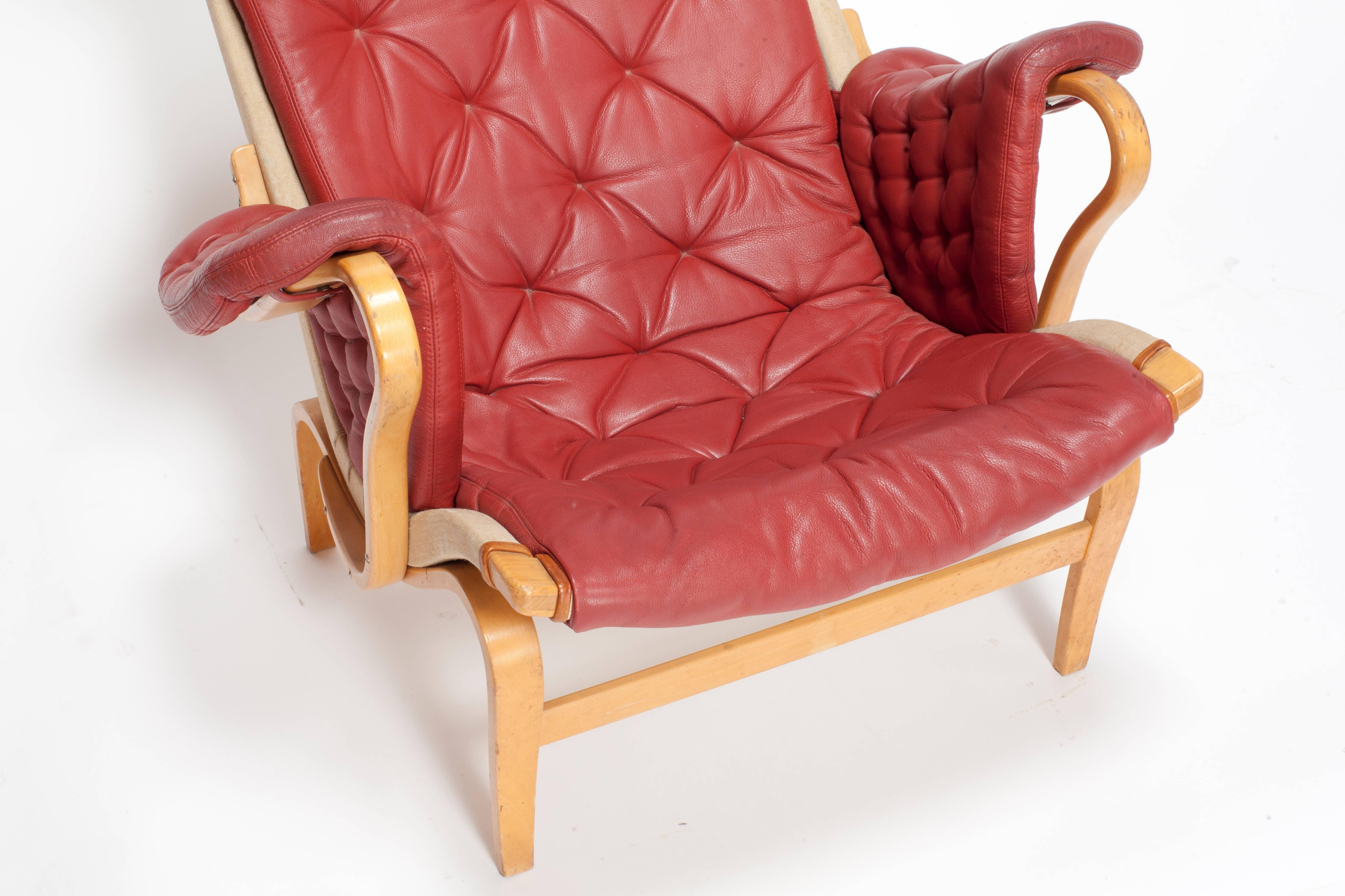 This Bruno Mathsson 'Pernilla' series lounge chair, comes with cushioned seats and headrests in tufted Red leather, against linen and bentwood frames in beech. The piece remains in overall good vintage condition, with presence of wear to original