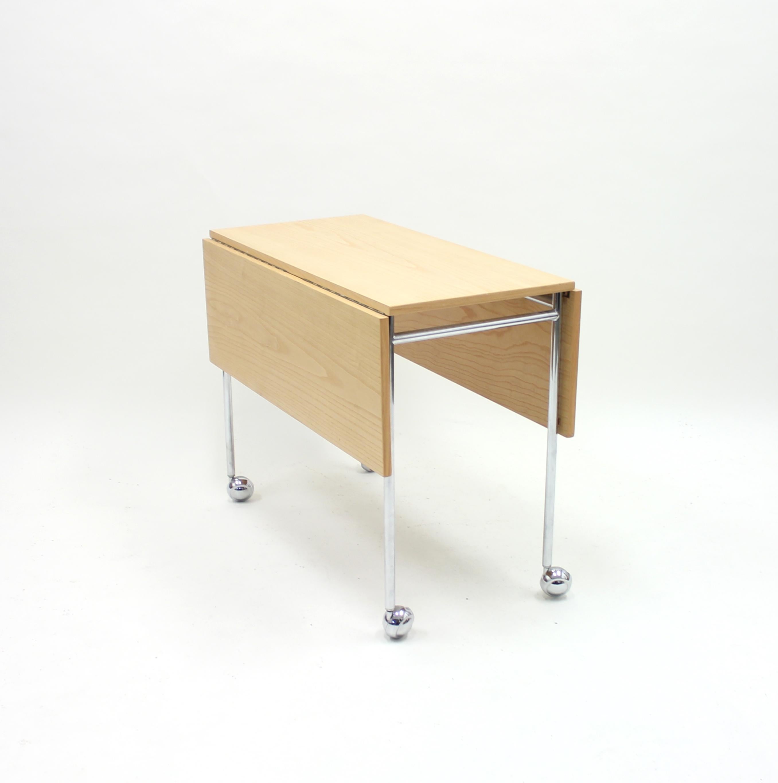 Side table / folding table, model Berit, designed by Bruno Mathsson in the 1960s for Mathsson International AB. This example is from the 1980s. Table top of ash with chrome plated legs on wheels. The holding mechanism for the leafs has a leather