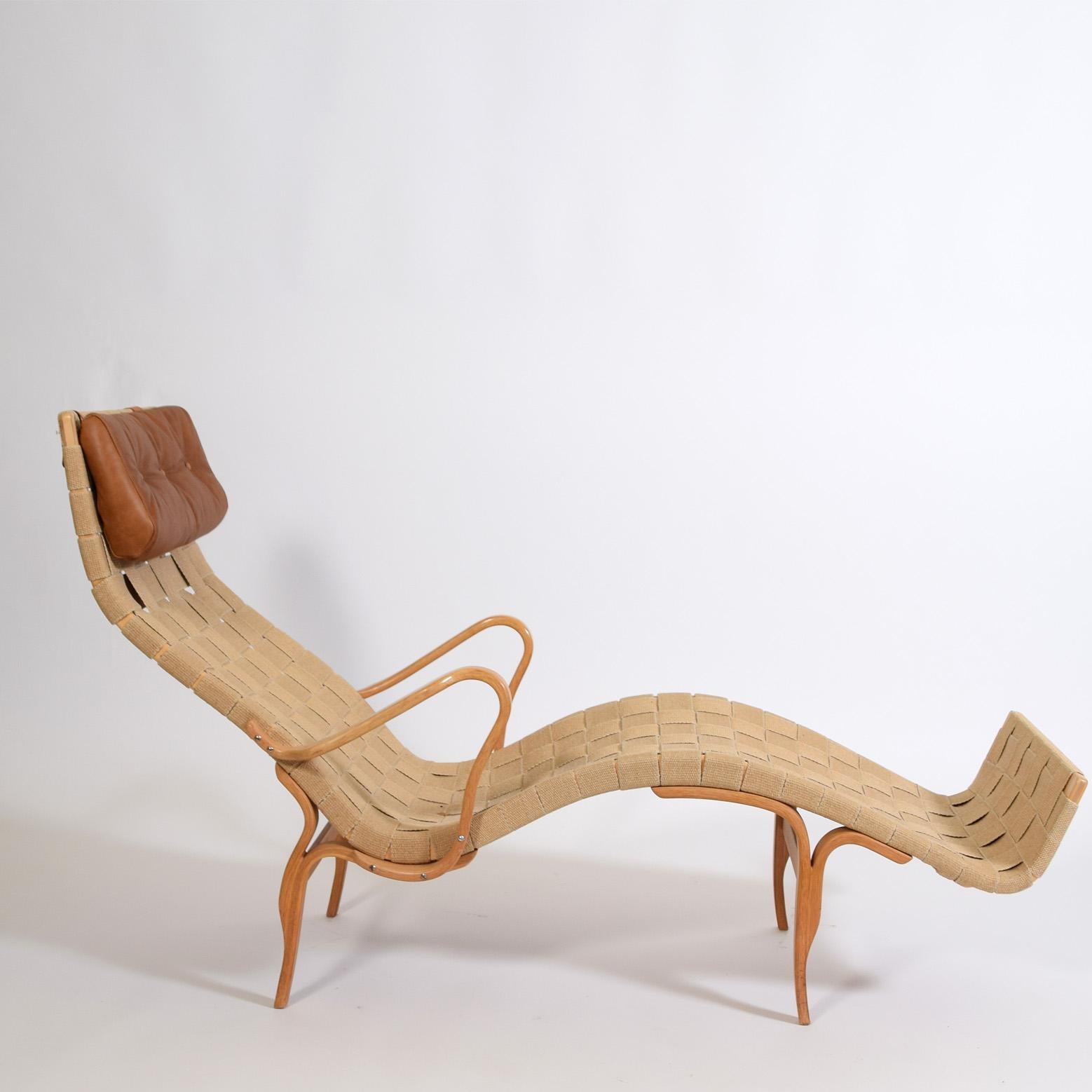 Iconic chaise longue by Swedish designer Bruno Mathsson, in bent birchwood with canvas weave fabric and brown leather head rest, designed in 1960's, Scandinavian modern.