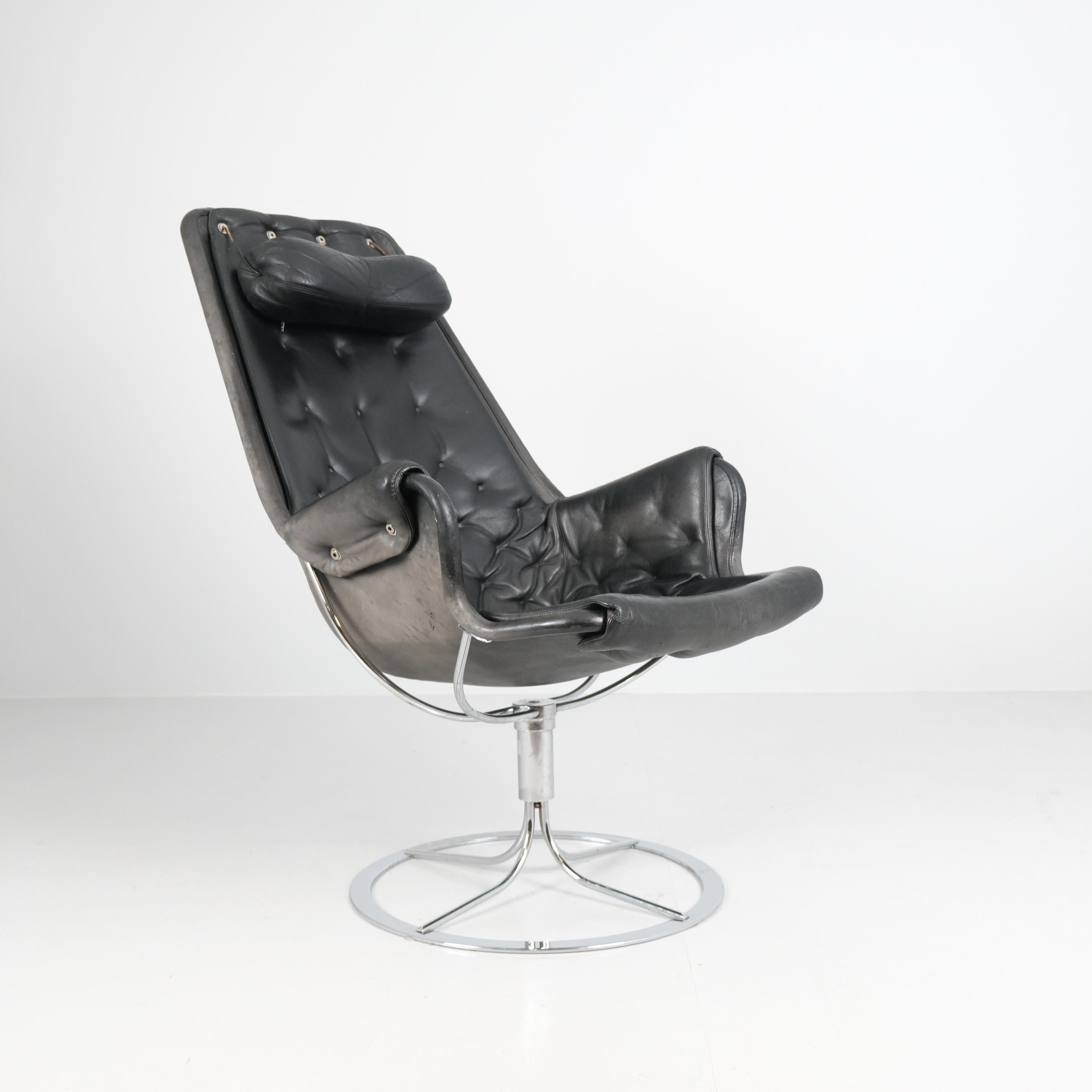 Un buen ejemplo de la icónica tumbona Jetson, diseñada por Bruno Mathsson para DUX, con su característica forma escultural, base de acero cromado y tapicería original de cuero negro. La silla conserva la etiqueta del fabricante con el nombre de