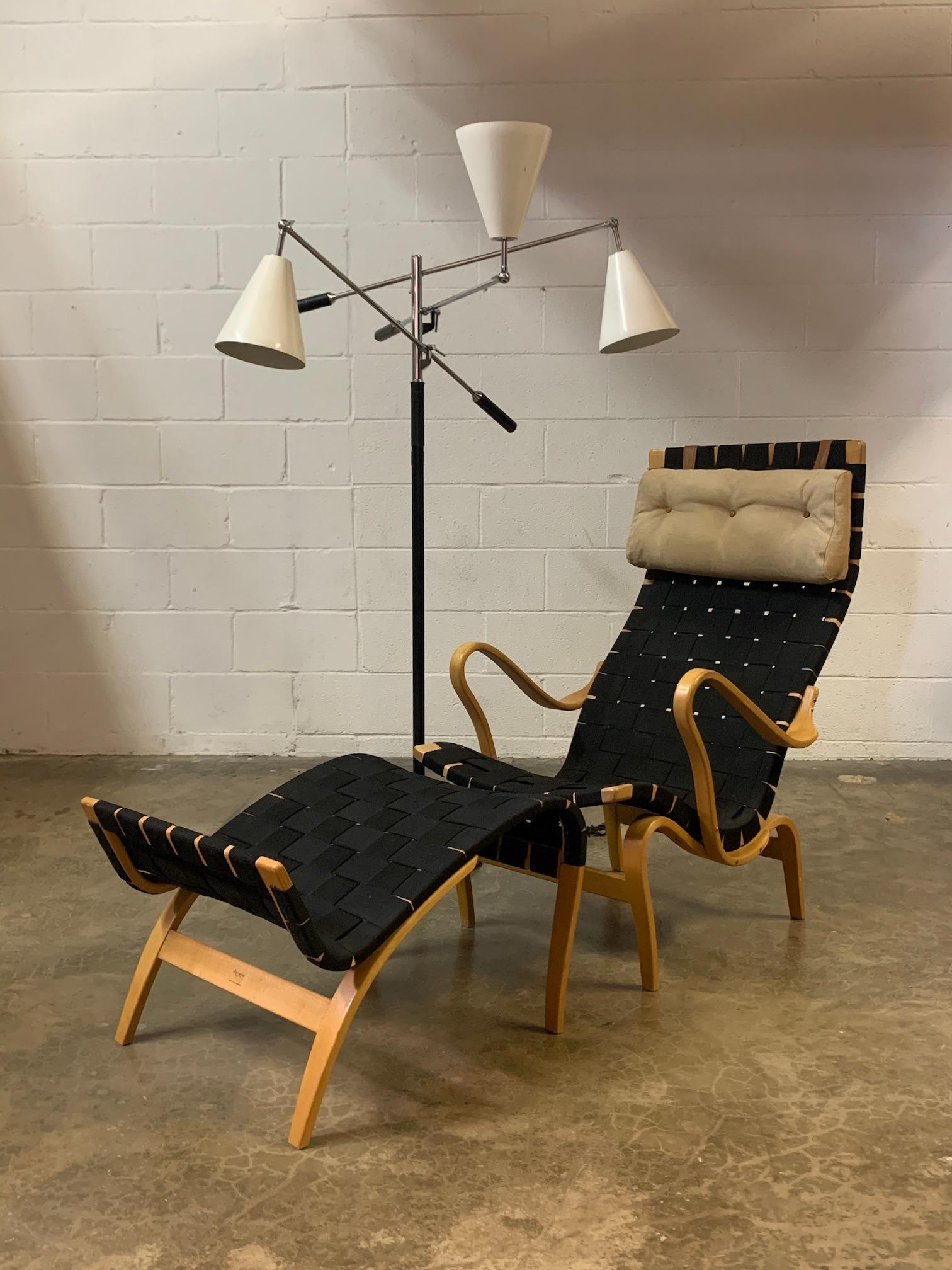 A lounge chair any ottoman designed by Bruno Mathsson. Beech frame with original black webbing and linen/leather pillow.