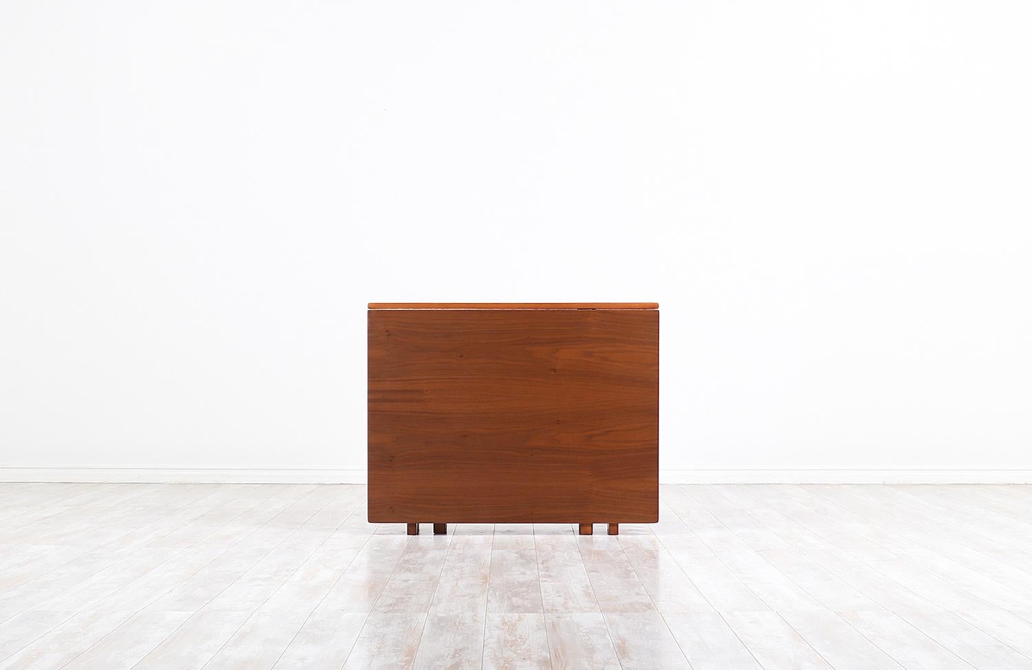 Stunning modern “Maria Flap” dining table designed by Bruno Mathsson for Karl Mathsson in Sweden, circa 1930s. This iconic Swedish Modern design features a stunning walnut wood top, a solid walnut-stained beechwood base, and brass hardware to give
