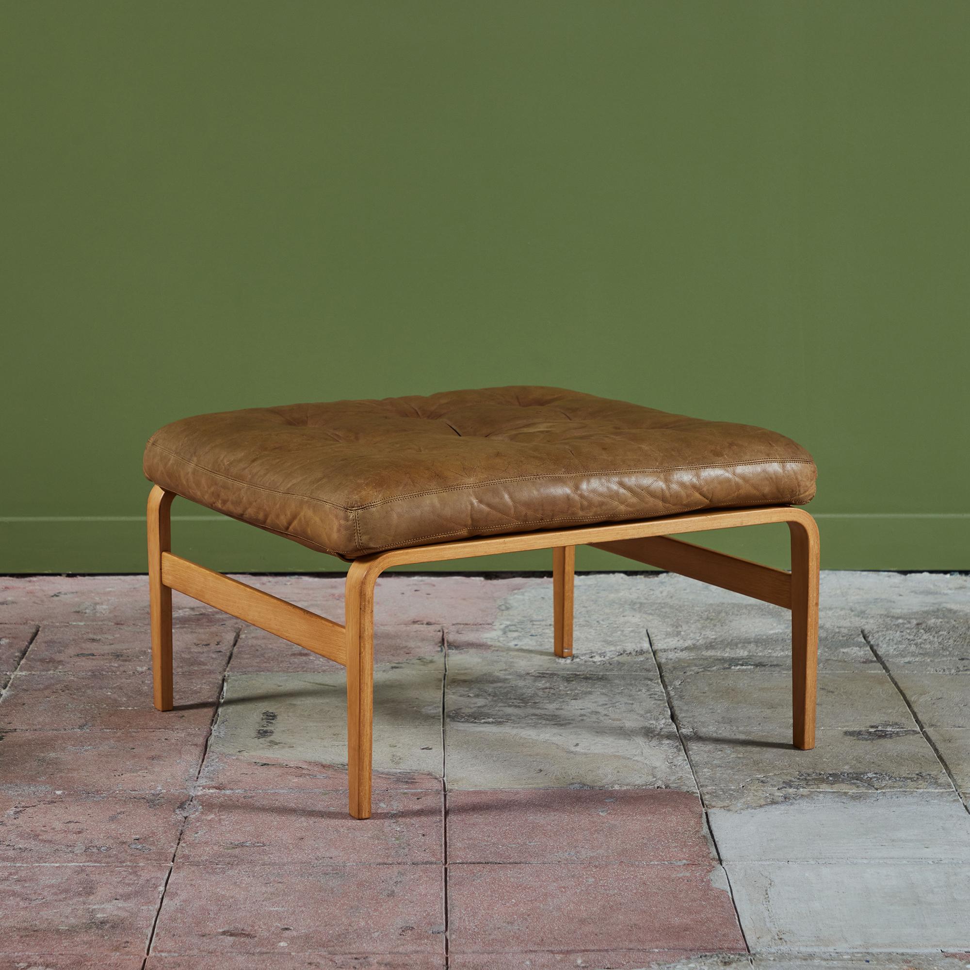 Ottoman by Bruno Mathsson for DUX, c.1960s, Sweden. The ottoman was originally paired with the Ingrid armchair. This piece features a tufted caramel leather seat on a bent beech wood frame.

Dimensions 
27” width x 27” depth x 15.5”