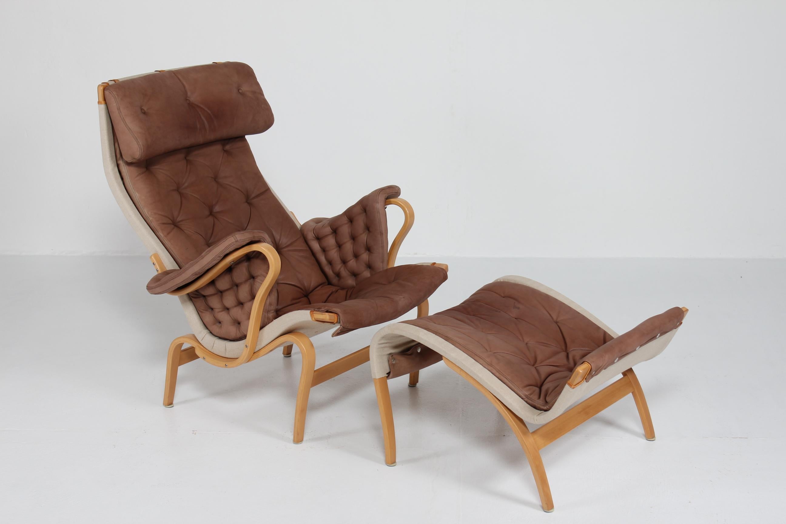 Scandinavian modern easy chair/ lounge chair with foot stool model Pernilla manufactured by Dux of Sweden. 
Designed by architect and designer Bruno Mathsson in 1944.
The frame is made of steam bend beech with lacquer. 
The original cushions are