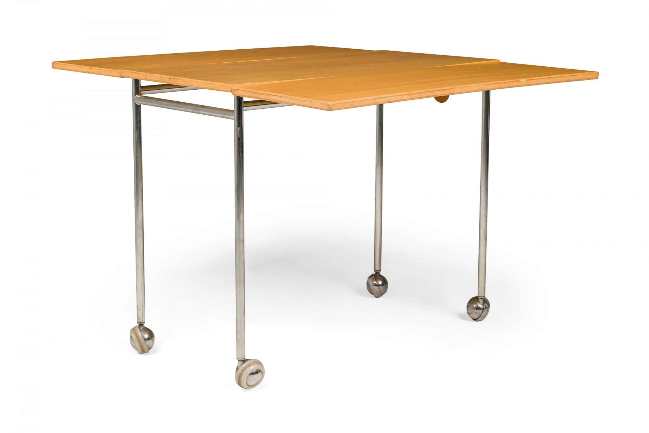 Swedish Mid-Century rectangular drop leaf work table with a rectangular wooden top and leaves resting on a steel frame with four legs ending in casters. (BRUNO MATHSSON)
