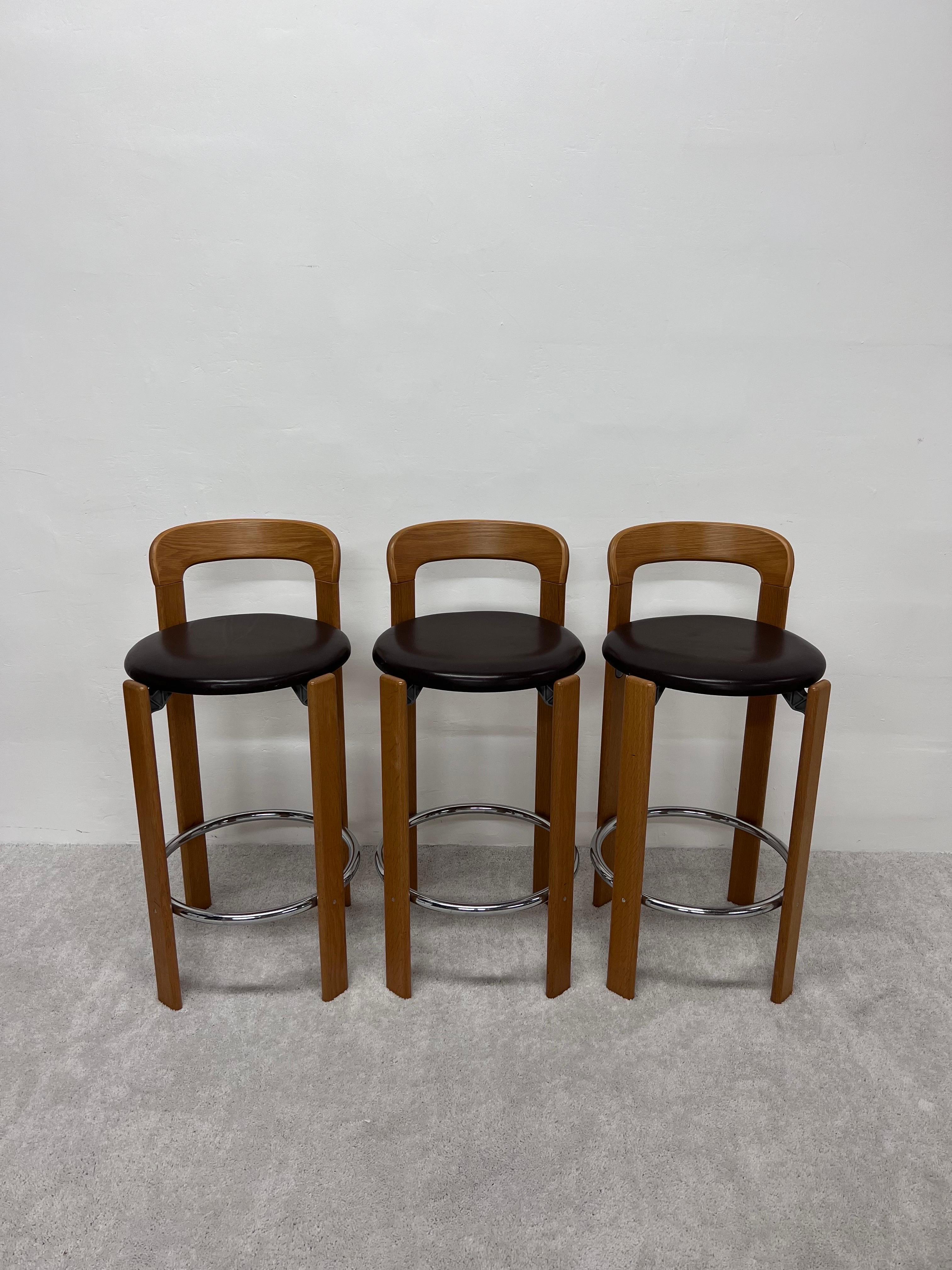 Rare set of three Bruno Rey bar stools with brown distressed leather seats on beech wood frames and tubular chrome foot rests. These chairs were manufactured in Stein am Rhein, Switzerland and licensed by Stendig. 

Designed by Bruno Rey, the Rey