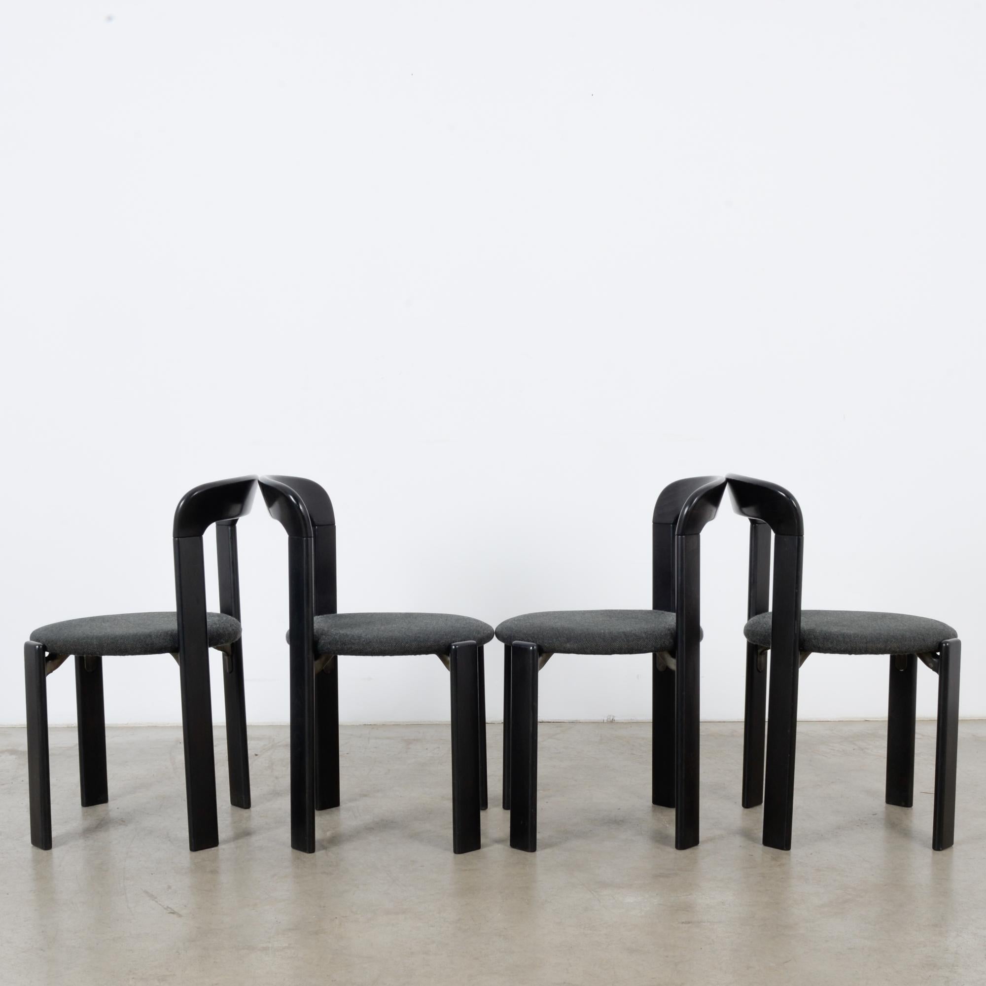 This set of four dining chairs was made in Germany, circa 1970. Designed by Bruno Rey for Kusch+Co, these stylish chairs have a black wooden frame and a charcoal gray upholstered seat. They feature four slim, rectangular legs and a curved top rail.