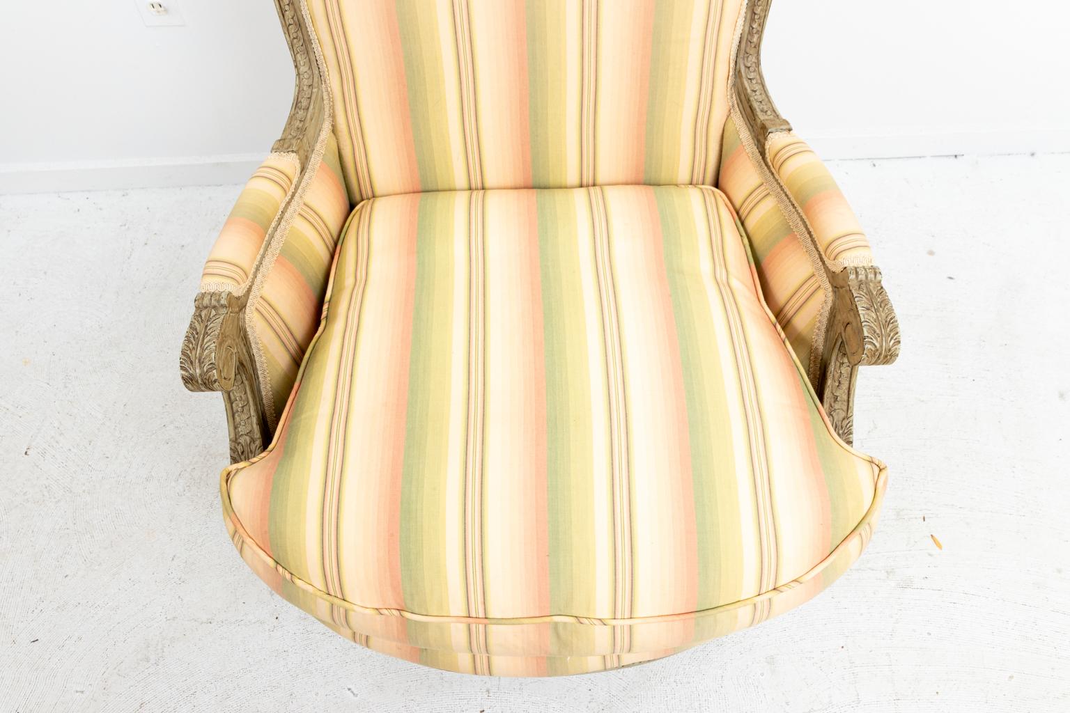 French bergère armchair upholstered in Brunschwig & Fils fabric, circa 1900s-1920s. The piece also features carved guilloche trim. Please note of wear consistent with age.