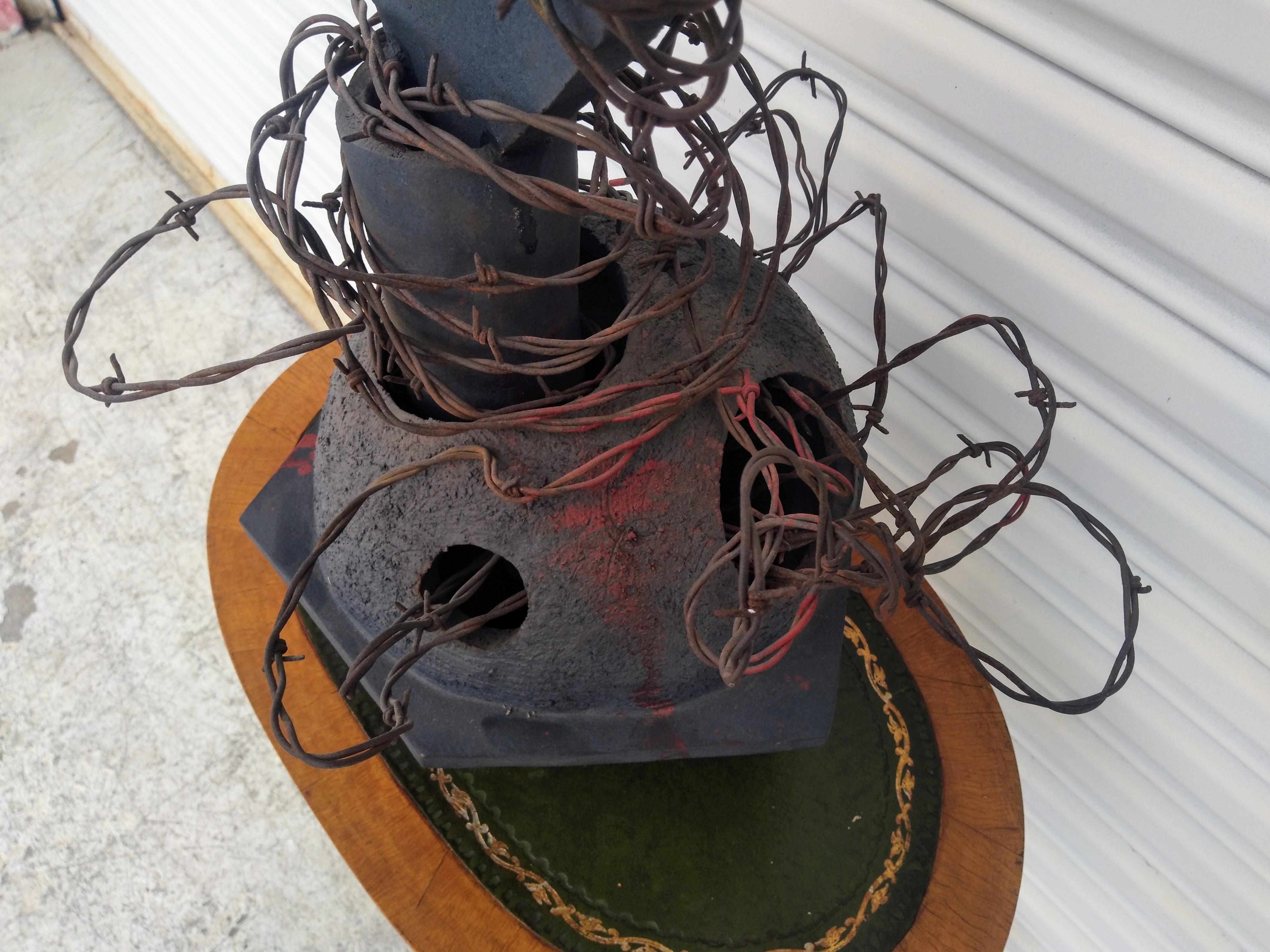 Questa è una bellissima scultura Raku di Bruny Graves. Ha una forma astratta con un filo spinato che la attraversa e la avvolge, conferendole un aspetto unico. 

Il raku è una tecnica tradizionale giapponese che utilizza un processo di cottura a