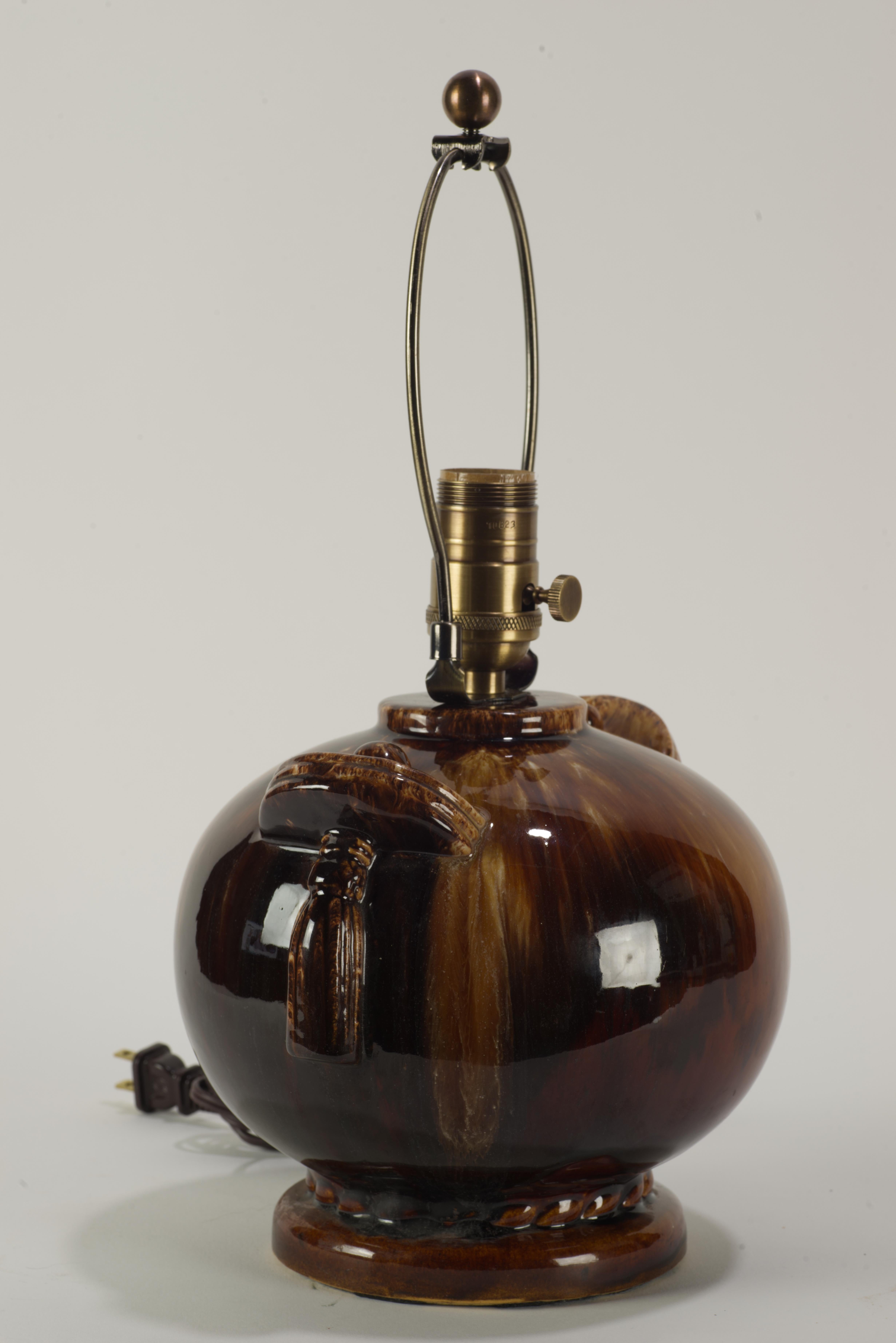  La lampe d'appoint en forme d'urne de style Art of Vintage est décorée d'une glaçure goutte à goutte graphique dans une palette de brun terreux ; les poignées sculpturales avec des détails de houppes n'altèrent pas les lignes épurées de la pièce
