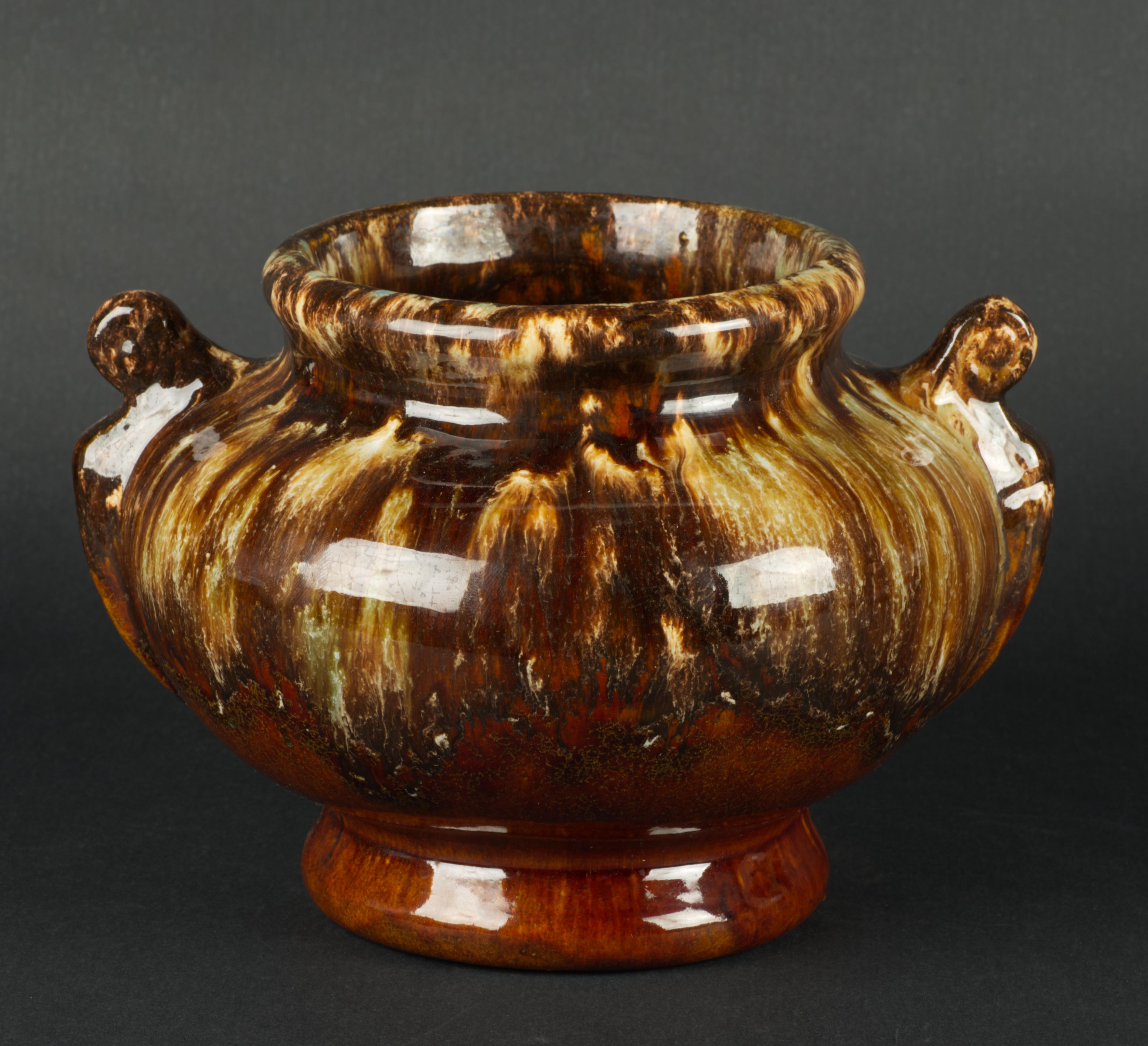  Il vaso d'epoca a forma di urna in stile Art Déco è decorato con smalti grafici a goccia in una palette di colori marrone terra; le superfici interne sono realizzate con smalti monocromatici solidi di colore marrone. Le maniglie arrotondate non