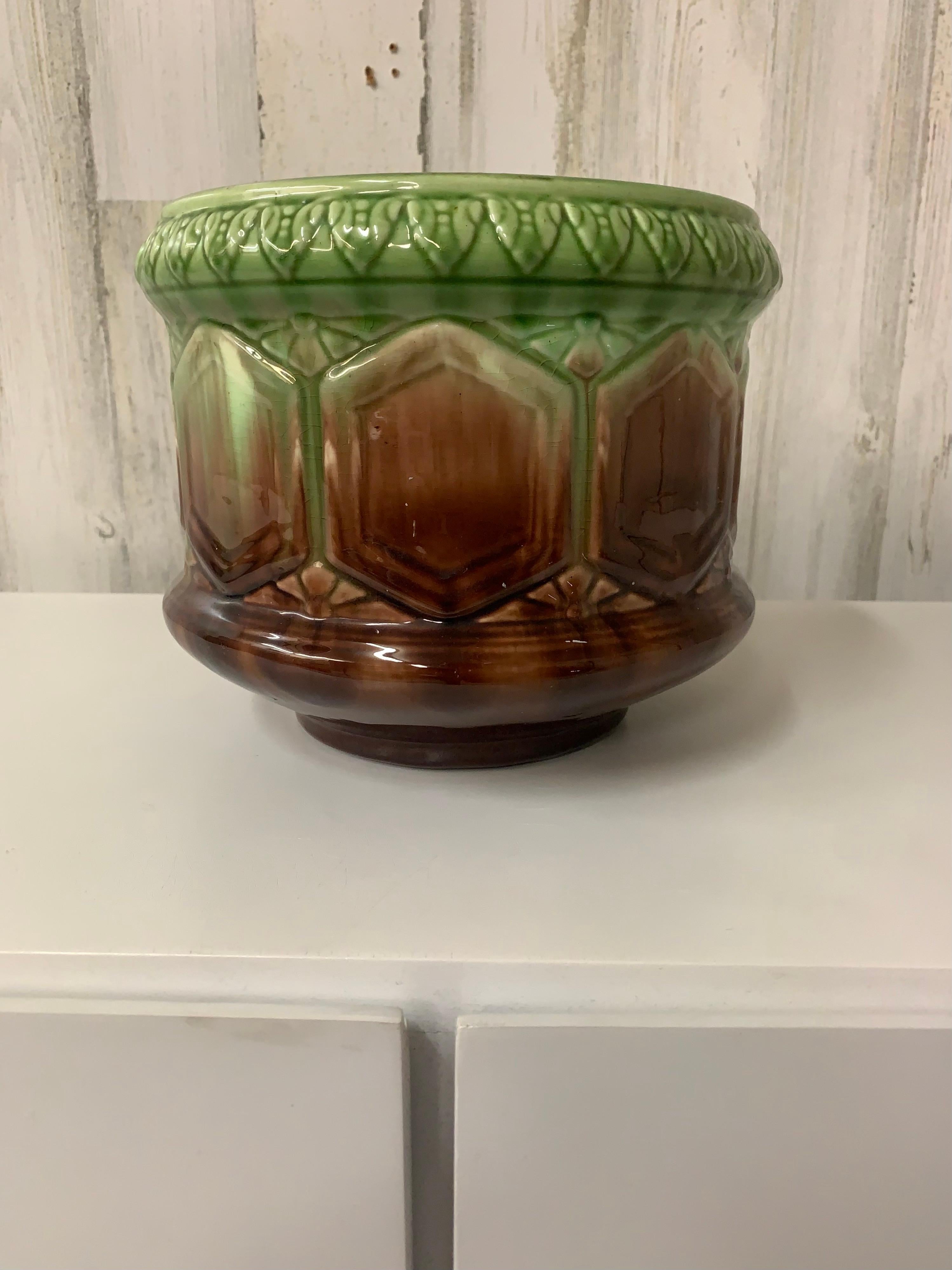 This antique Brush McCoy planter from the 1910s features a round shape with a multicolor blended majolica design. Made of ceramic, it stands 7 inches tall and wide, with a decorative pattern typical of the Edwardian era. Produced in the United