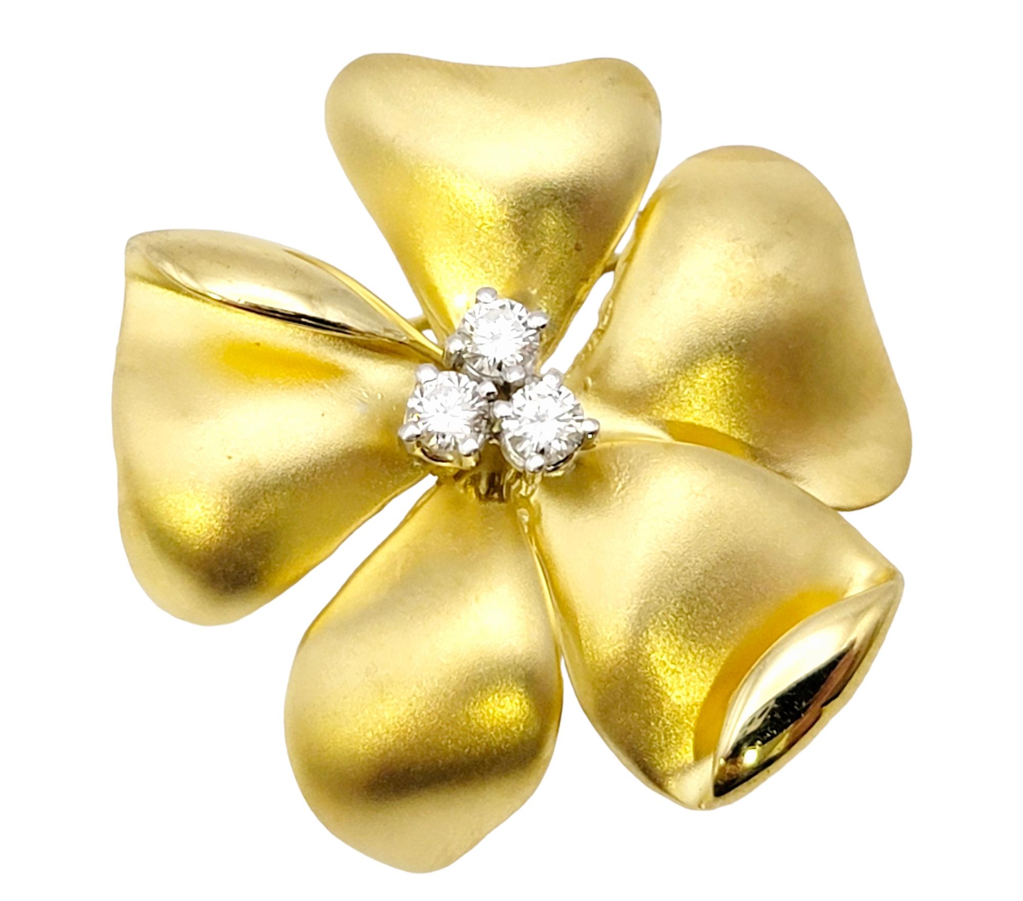 Elevate your style with this gorgeous brushed yellow gold flower brooch, adorned with three radiant diamonds. Crafted with meticulous attention to detail, this exquisite piece is a stunning testament to the artistry of fine jewelry. The brushed