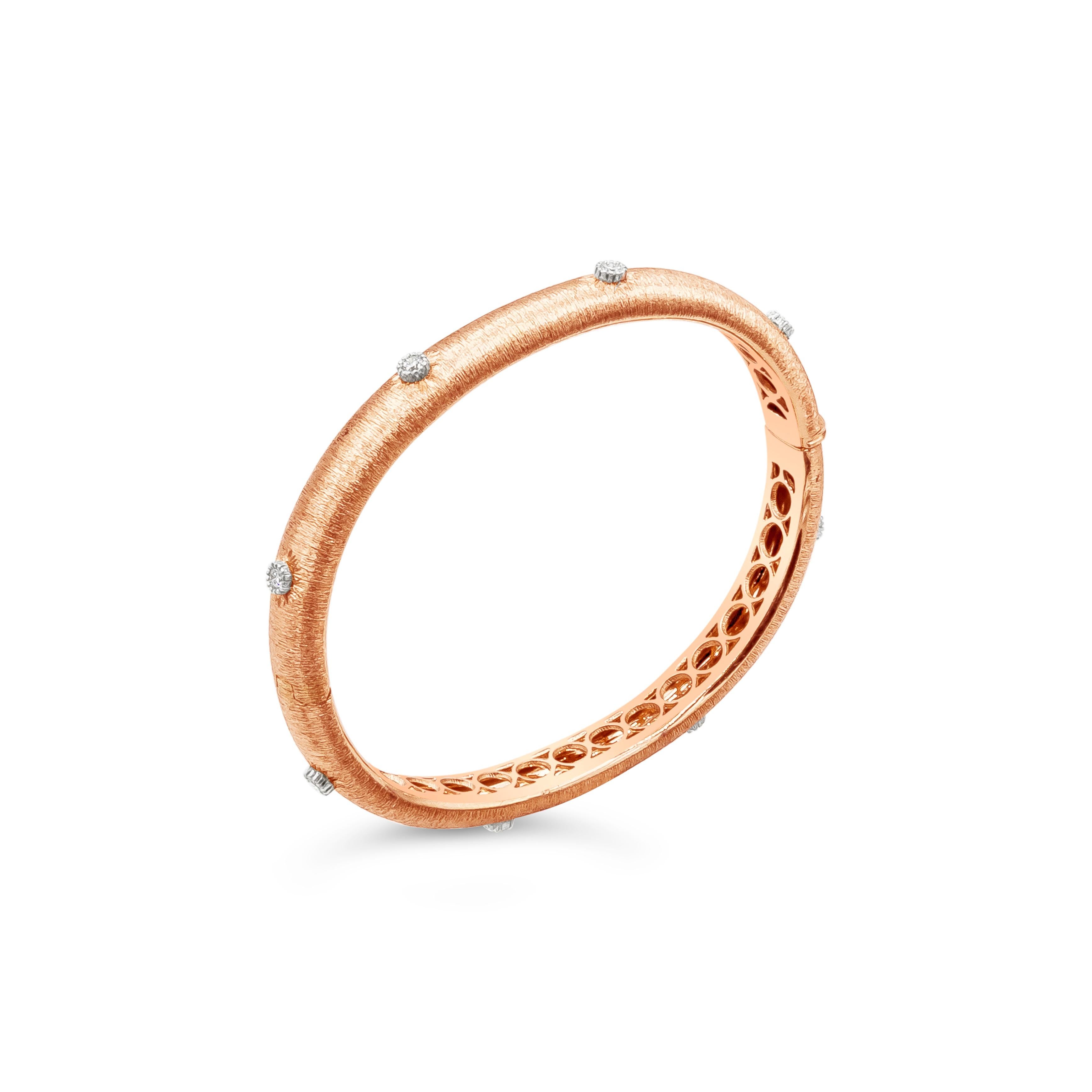 A fashionable bangle bracelet showcasing round brilliant diamonds weighing 0.45 carats total, set in a domed and brush finished bangle made in 18k rose gold.

