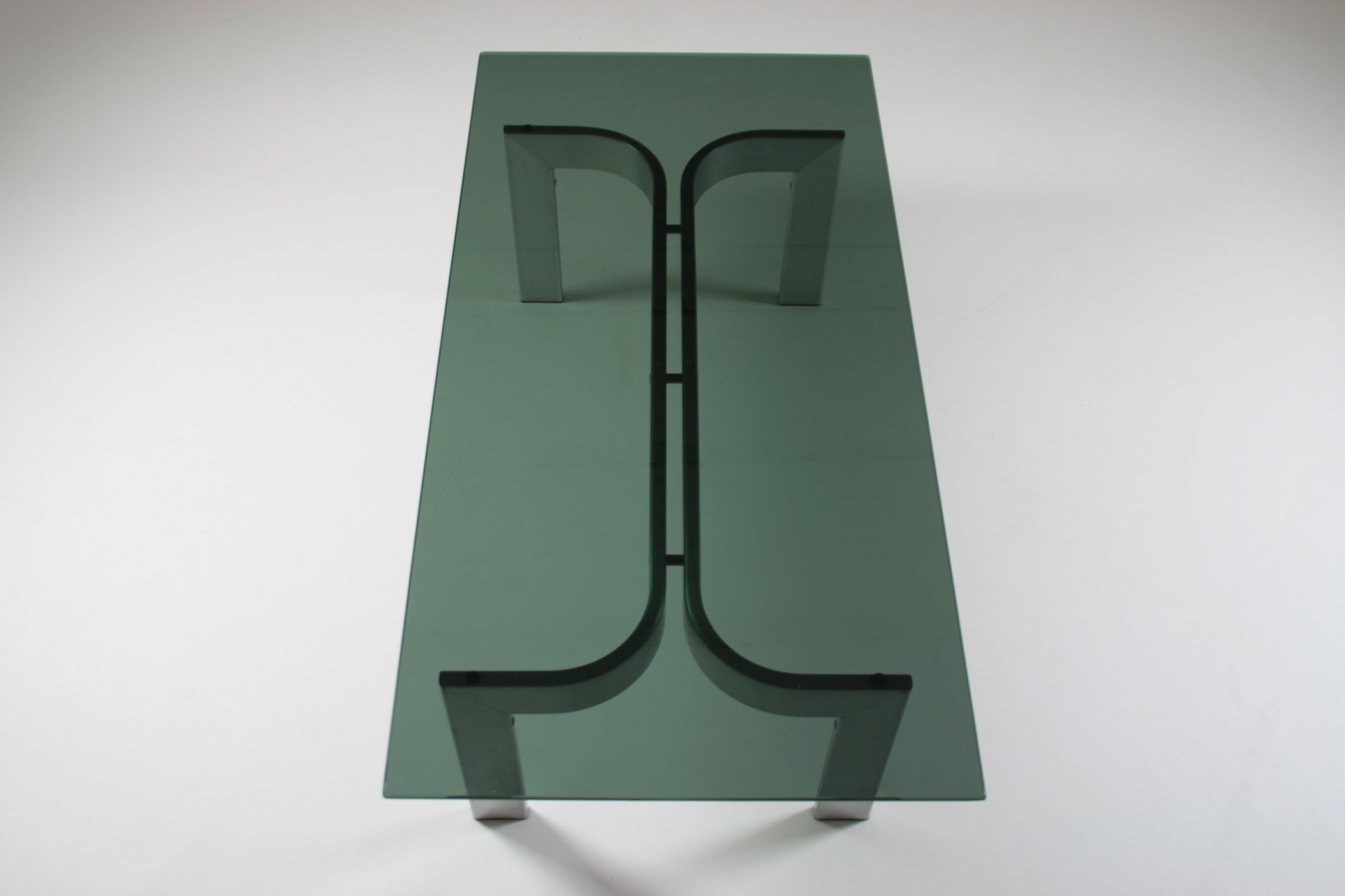 Table basse rectangulaire avec pieds en aluminium brossé et éditée en France dans les années 1970. Plateau en verre fumé avec quelques micro-rayures d'utilisation mais qui restent superficielles. Bon état général. Dimensions : D120 X W60 X H37 cm.