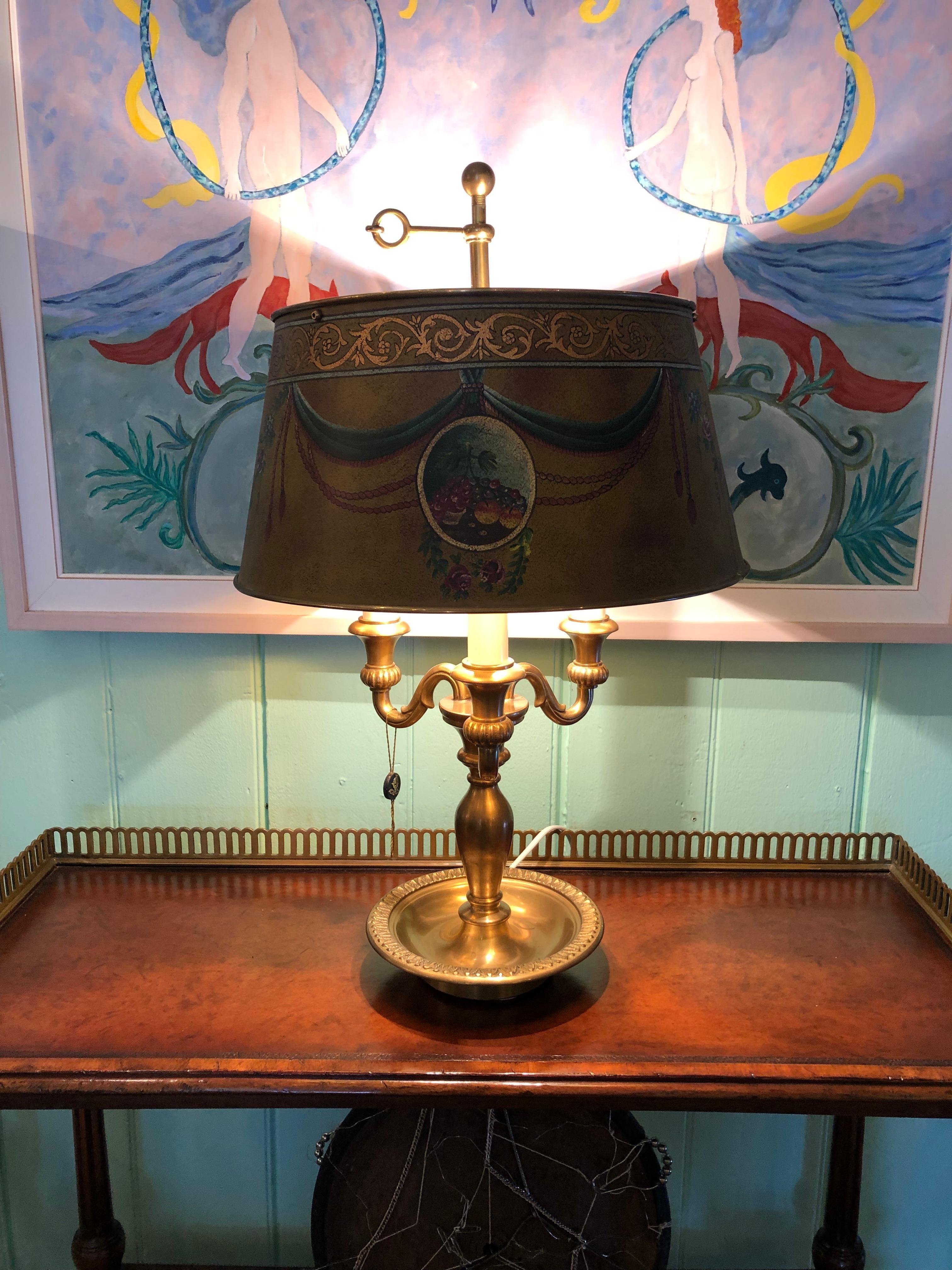 Beautiful two arm brushed brass bouillotte table lamp having striking paint decorated metal shade.
