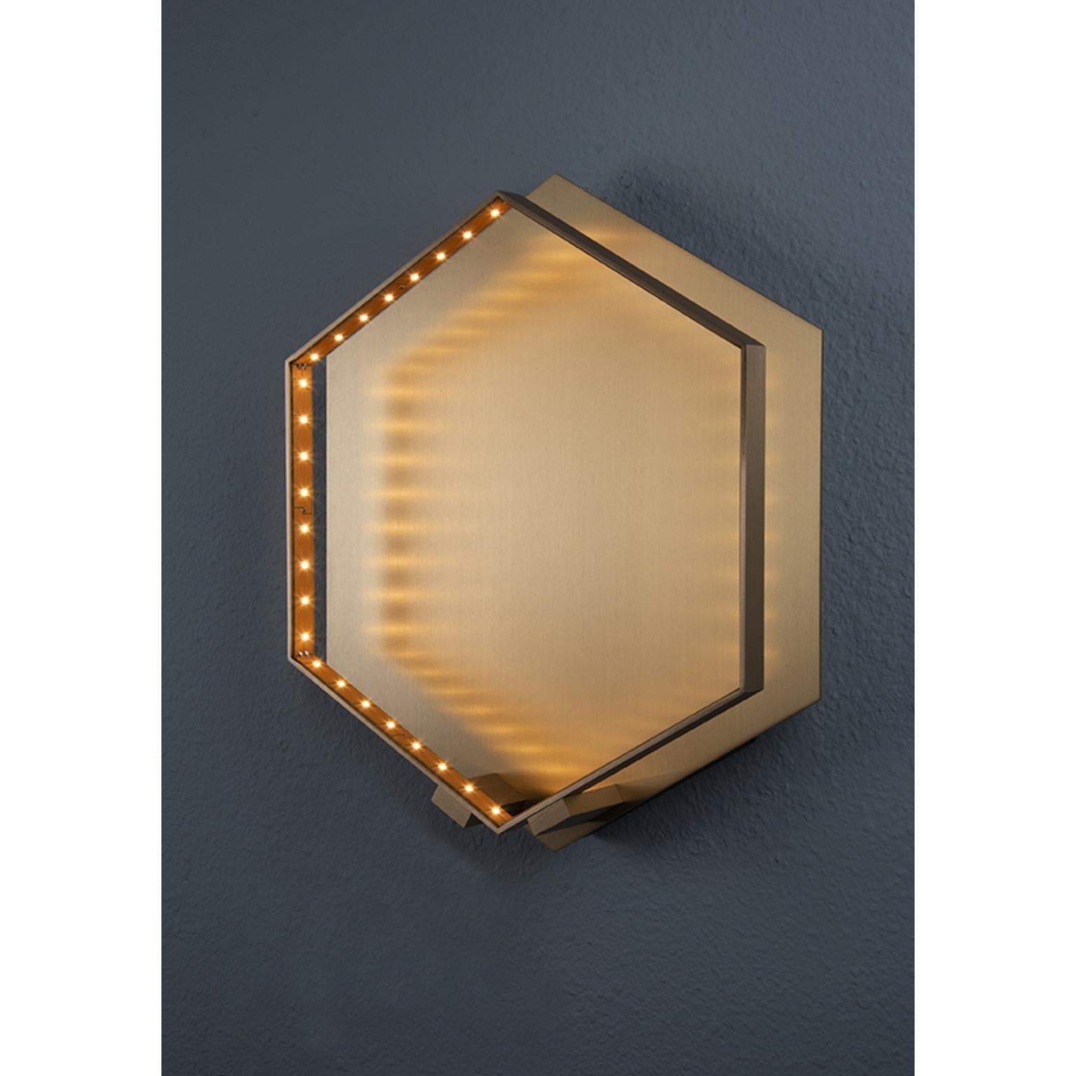 Lampada da parete Hexa in ottone spazzolato di Le Deun Luminaire
Dimensioni: L 32 x P 8 x H 36 cm. 
Materiali: Ottone massiccio con rivestimento galvanico opaco.

Si tratta di un'azienda francese fondata nel 1997, specializzata nella progettazione e