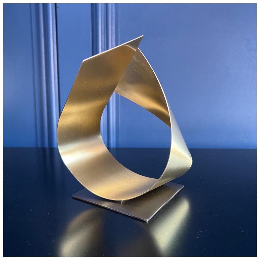 The FLUX sculpture is a smaller version of the FLUX table lamp. A beautiful piece of art for your home. Perfect for a study or console table. Rolled from a single piece of solid brushed brass and mounted on a brushed bronze base. The perfect