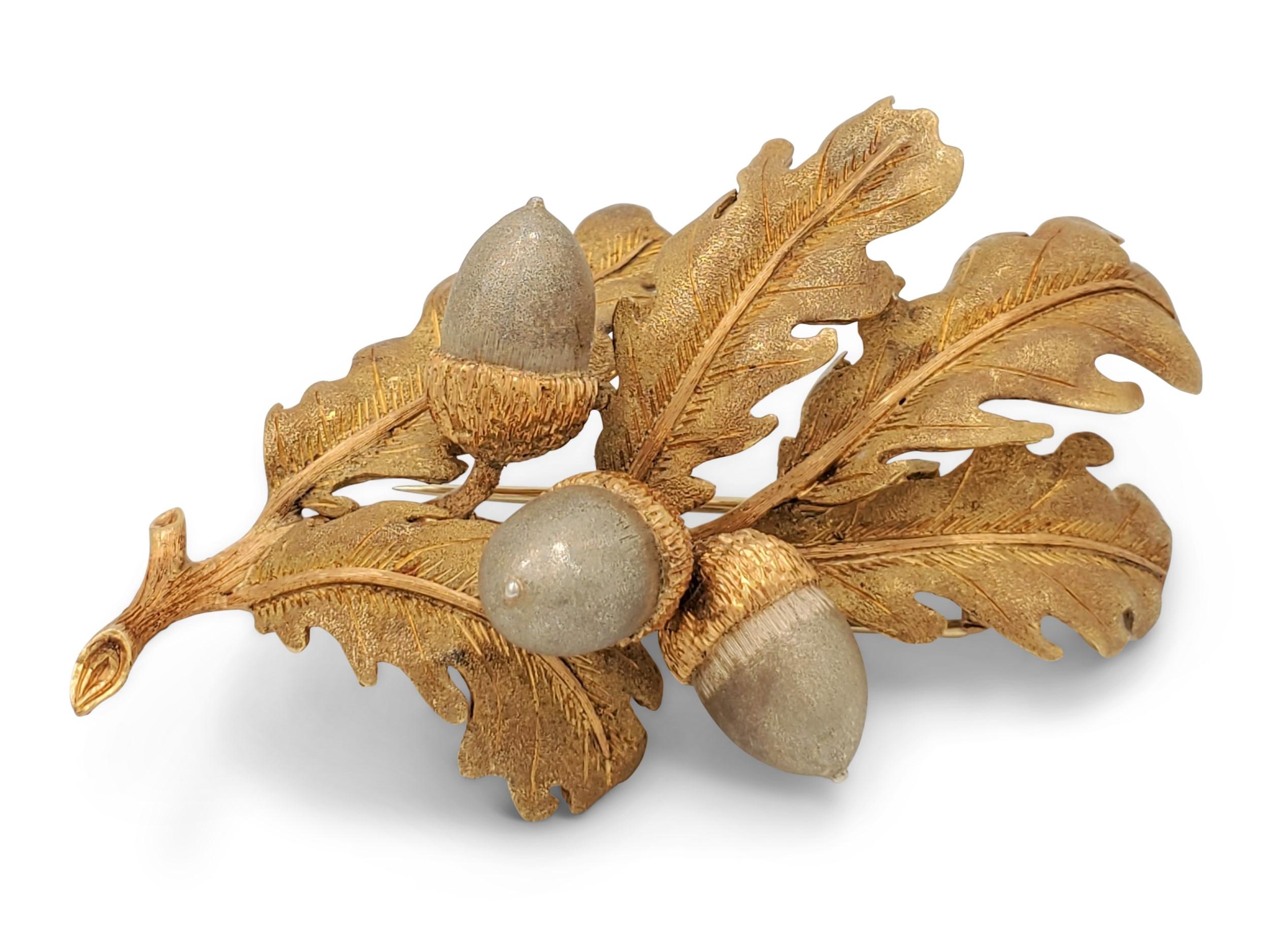A brooch designed as a series of brushed 18 karat yellow gold oak leaves with three acorns hanging off to the sides. The vein detail on leaves and stems are smooth-polished gold, which adds to the design. The acorns are crafted in brushed 18 karat