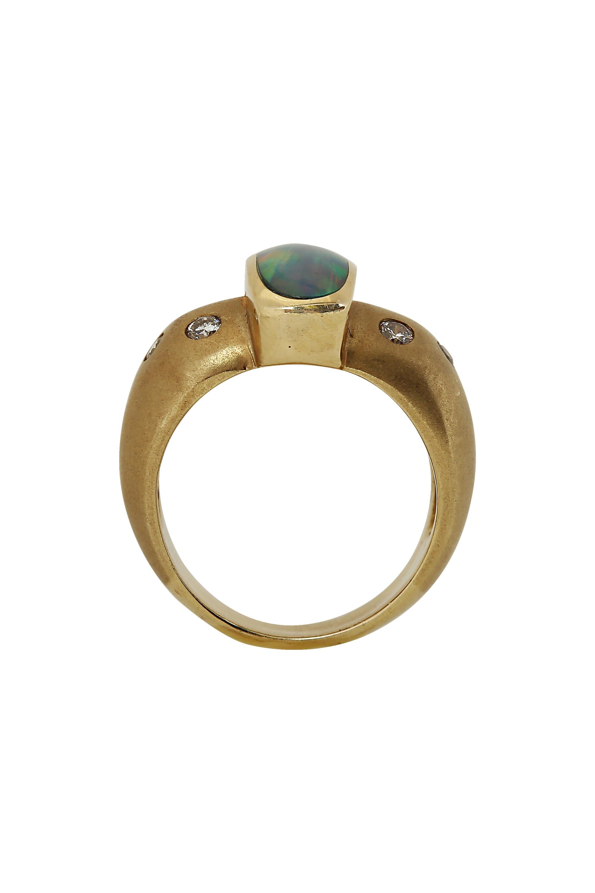 This striking and modern ring features and elongated opal with a vibrant interplay of glowing colors set in a polished and matte finished 14 karat yellow gold mounting studded with flush set diamonds. Total diamond weight is approximately .20