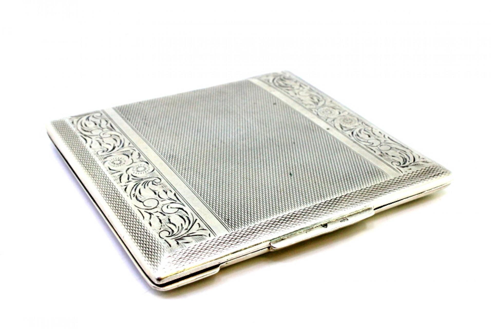 Description: Brushed silver toiletry box with engraved floral motifs, mirror inside and bands throughout. Metal: Silver. Origin: European. Brand: Unknown. Weight: 140.45 grams. Dimensions: 8.5cmx8.3cm. Content: 835/1000. Assay Mark: Yes. Additional