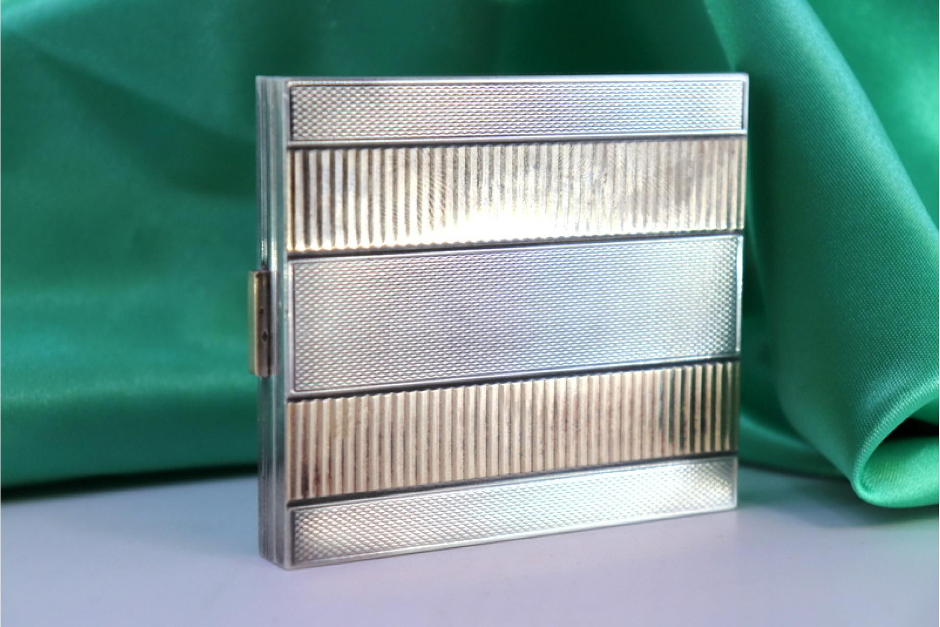 Description: Brushed silver toiletry box with gold bands and interior mirror with powder container. Metal: Gold - Silver. Origin: French. Brand: Boar's Head. Weight: 155.61 grams. Dimensions: 8cm x 7cm. Content: 750/1000 (Gold) - 950/1000 (Silver).