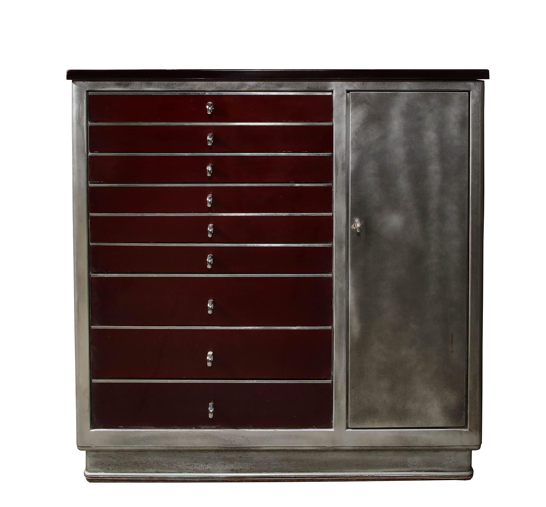 The brushed steel Cabinet with an enamel top over a 9 enameled drawers and 1 brushed steel door on the front side and an all brushed steel back with 3 doors and a fall front drawer. All with chrome pulls.