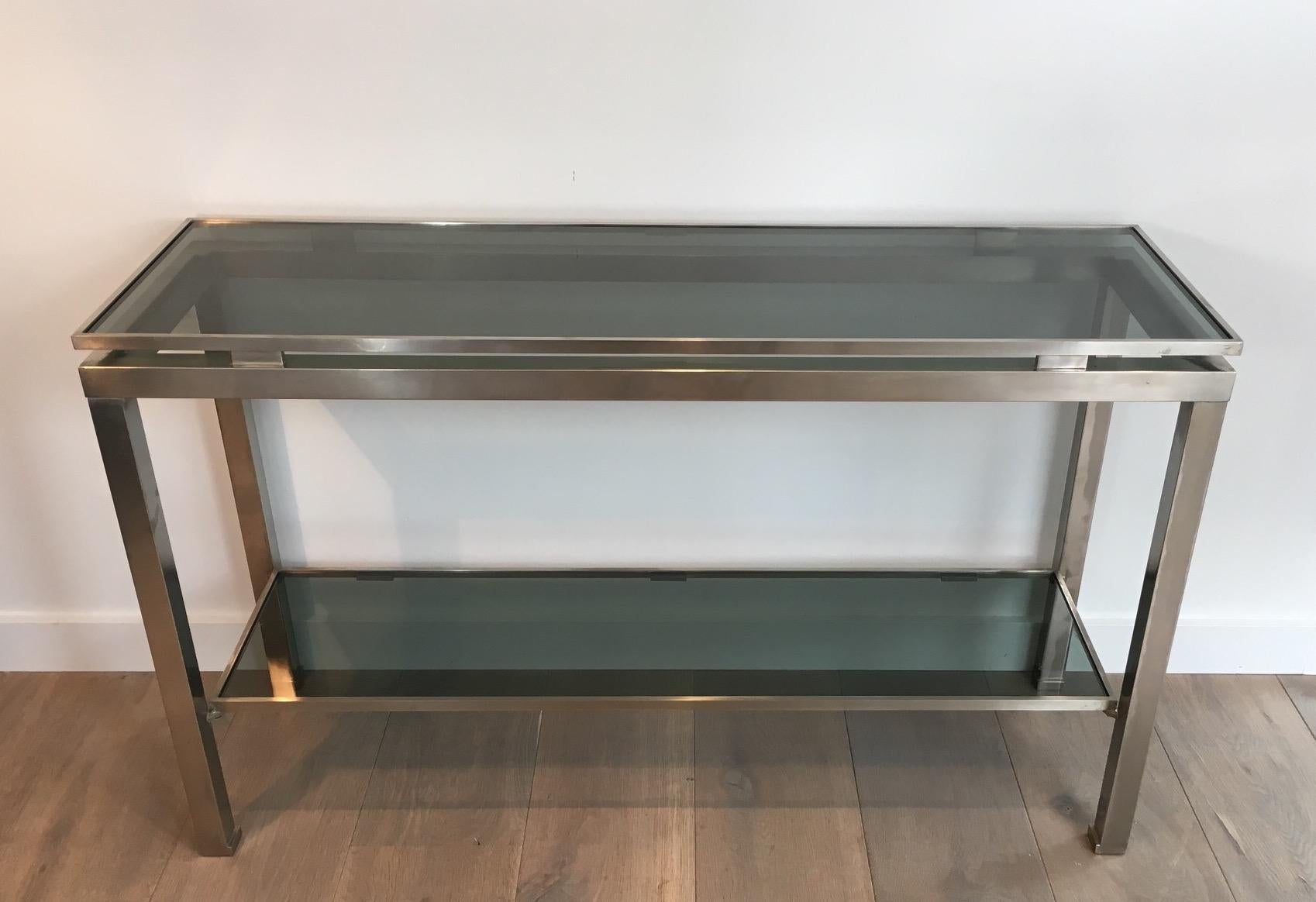 This very nice console table is made of brushed steel. It has nice blueish glass shelves. This model is by famous designer Guy Lefèvre for Maison Jansen. Circa 1970.