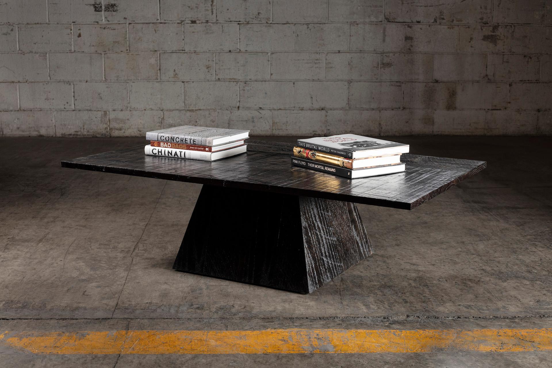 Cette table basse moderne en chêne massif avec une base triangulaire et une finition esthétique noire dramatique, donne à chaque espace où vous la placez un look moderne et unique. 
Inspiré du Brutalisme des années 1970. Fabriqué à la main par des