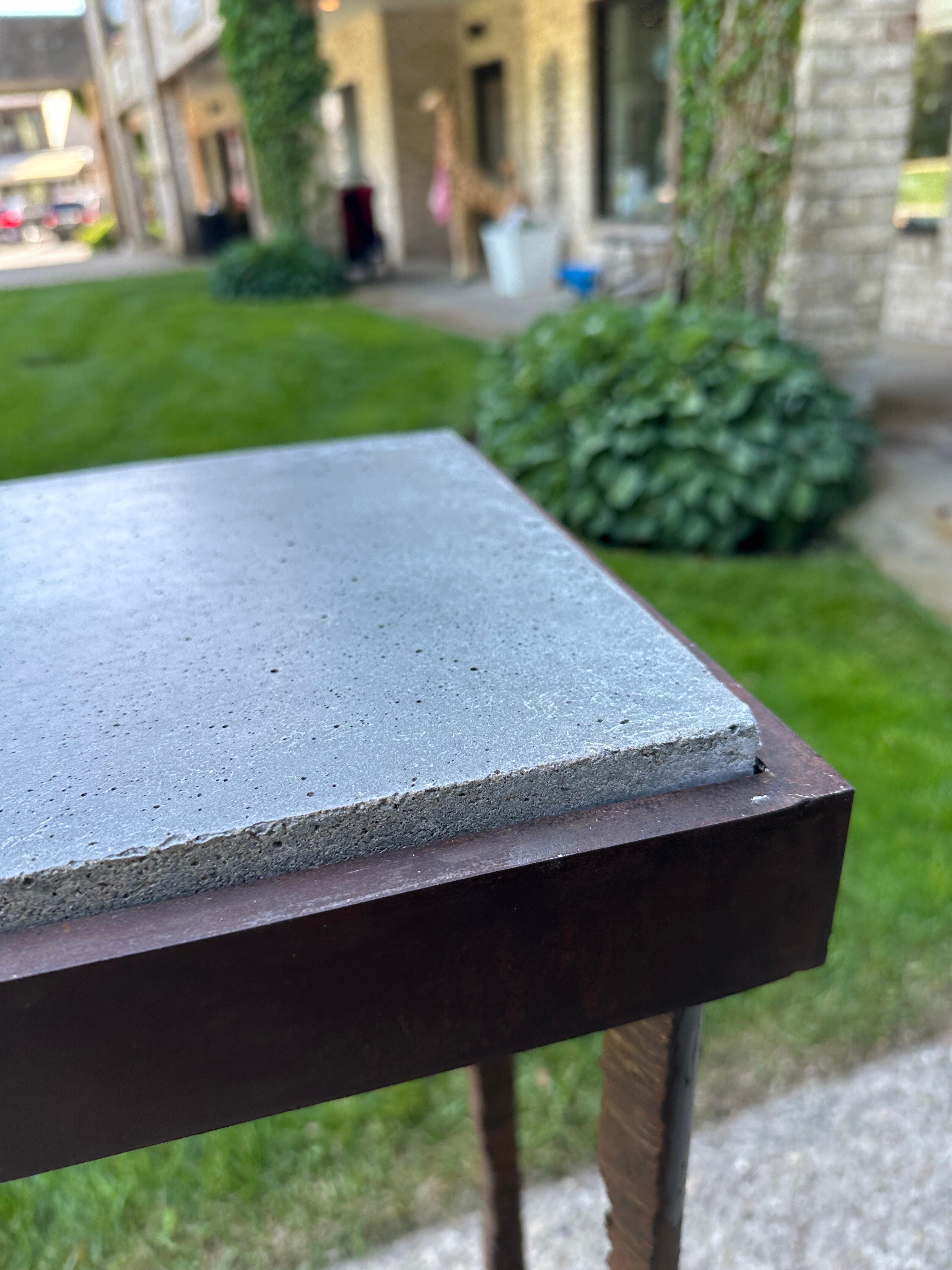 Expertly torch cut from a round solid piece of steel in to 4 legs which comprise this console.  Inset of gray slate tone concrete slab.  Very brutal and unique with natural oxidization makes the color perfectly authentic for any terrace or indoor