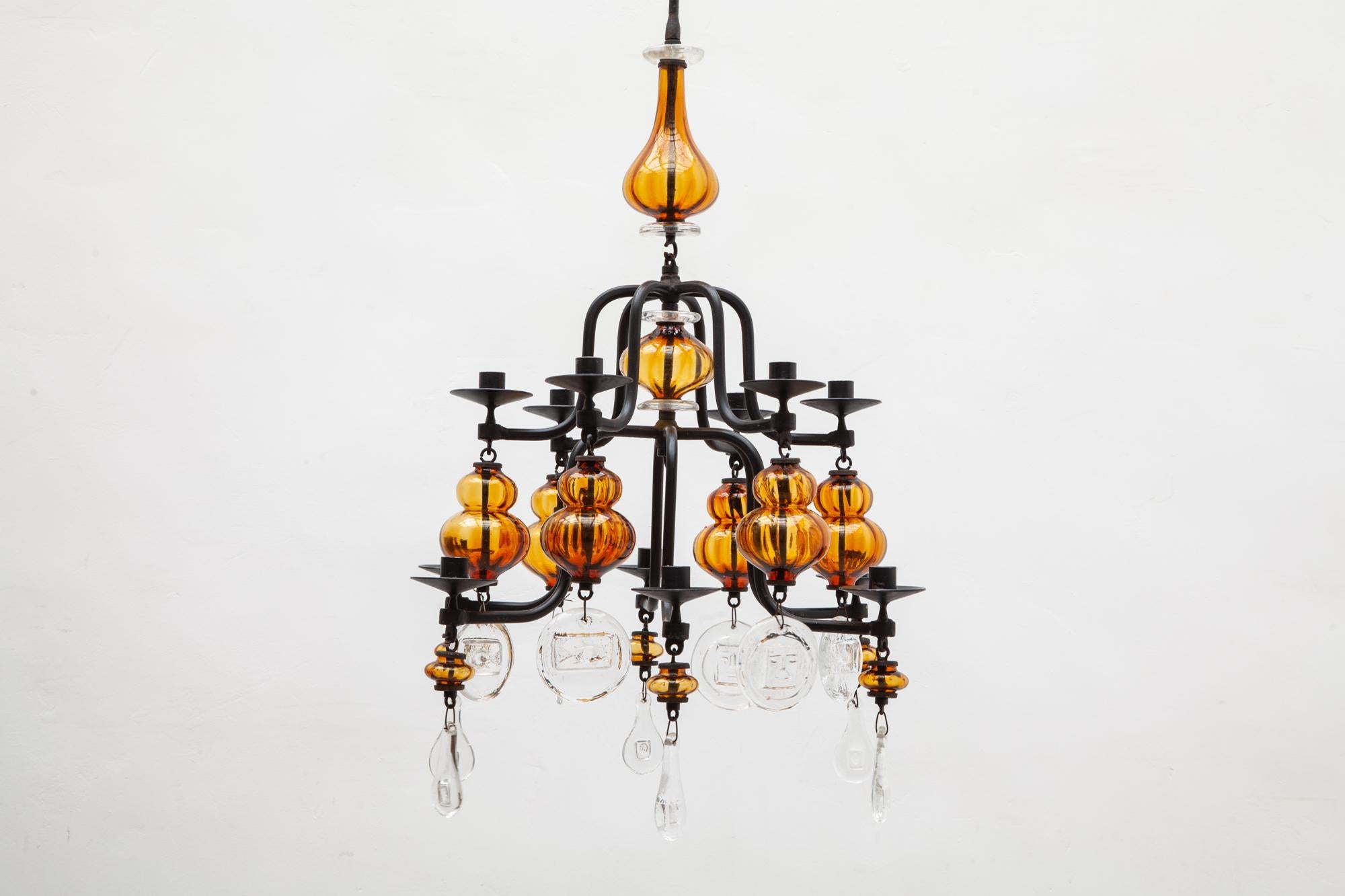 Wrought iron and clear glass 12-arm chandelier by Erik Hoglund, Boda. Cast iron, mouth-blown and pressed amber and clear glass 12-arm chandelier for 12 candles by Swedish designer Erik Hoglund with images of animals and faces. Boda Nova Glassworks,