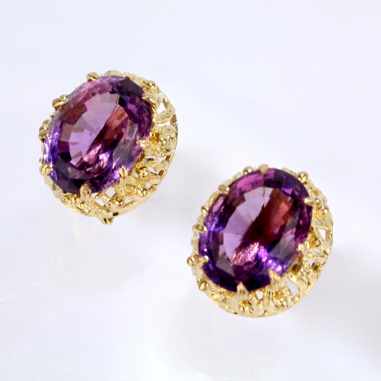 A very good pair of large 14k gold Brutalist omega clip earrings.

Each with a substantial oval-cut amethyst gemstones (10+ carat) prong set in a sinuous, intertwined structural 14k gold Brutalist setting. The gold settings have ample openwork that