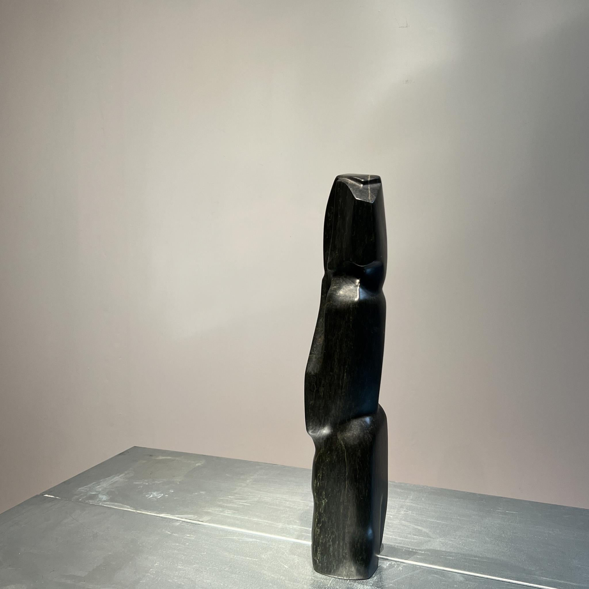 Large black stone sculpture of a figure in expressionist / brutalist style,
This sculpture  smooth hand carved textures emphasizes the strong abstract shapes of a human figure.

This sculpture with its rounded shapes, creating compositions that