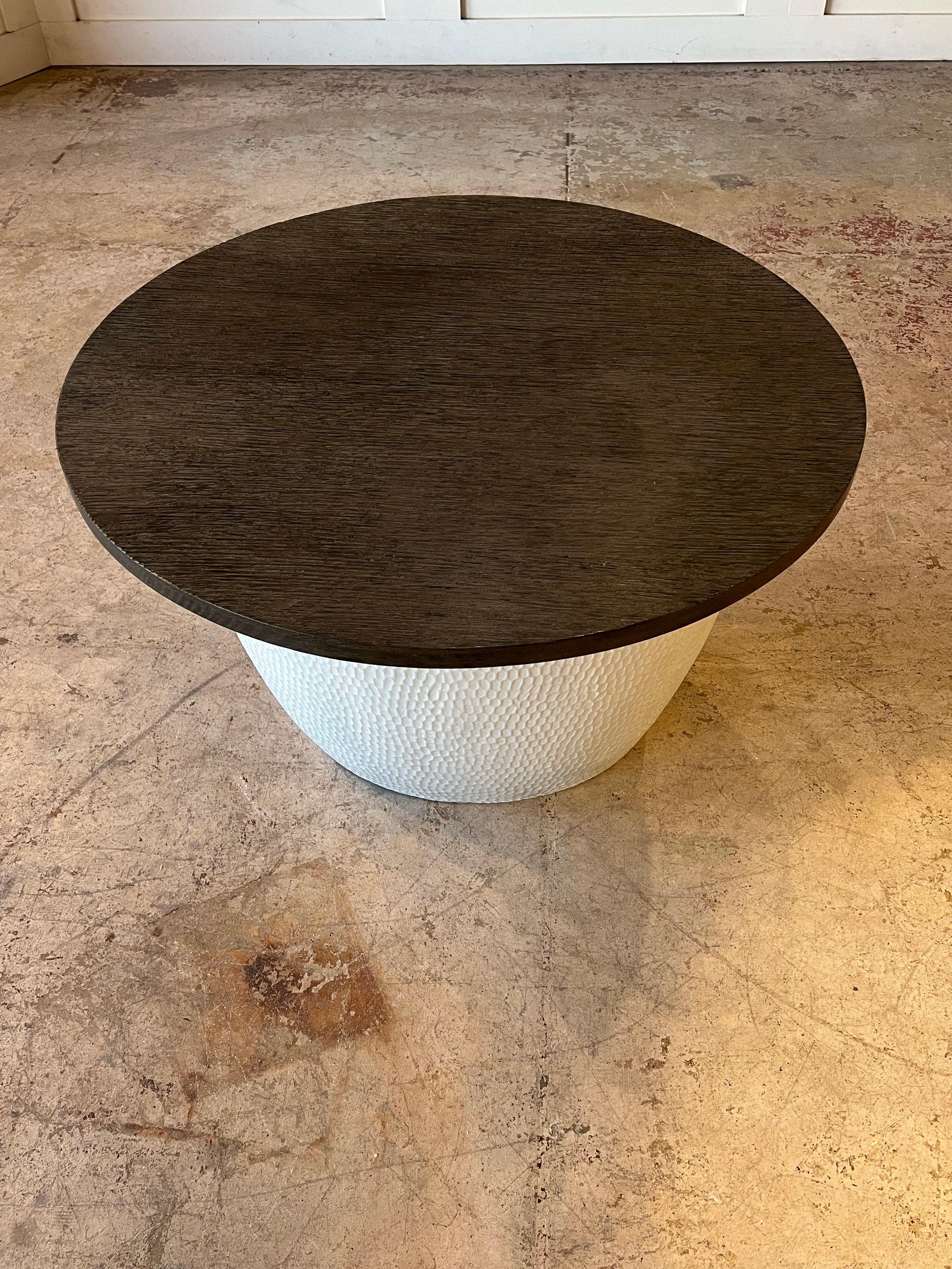 This table is a design piece crafted in the 1980s, boasting an elegant structure. One can immediately notice the striking contrast between the base, made of empty white concrete, and the removable dark brown eradicated wenge  top which was added