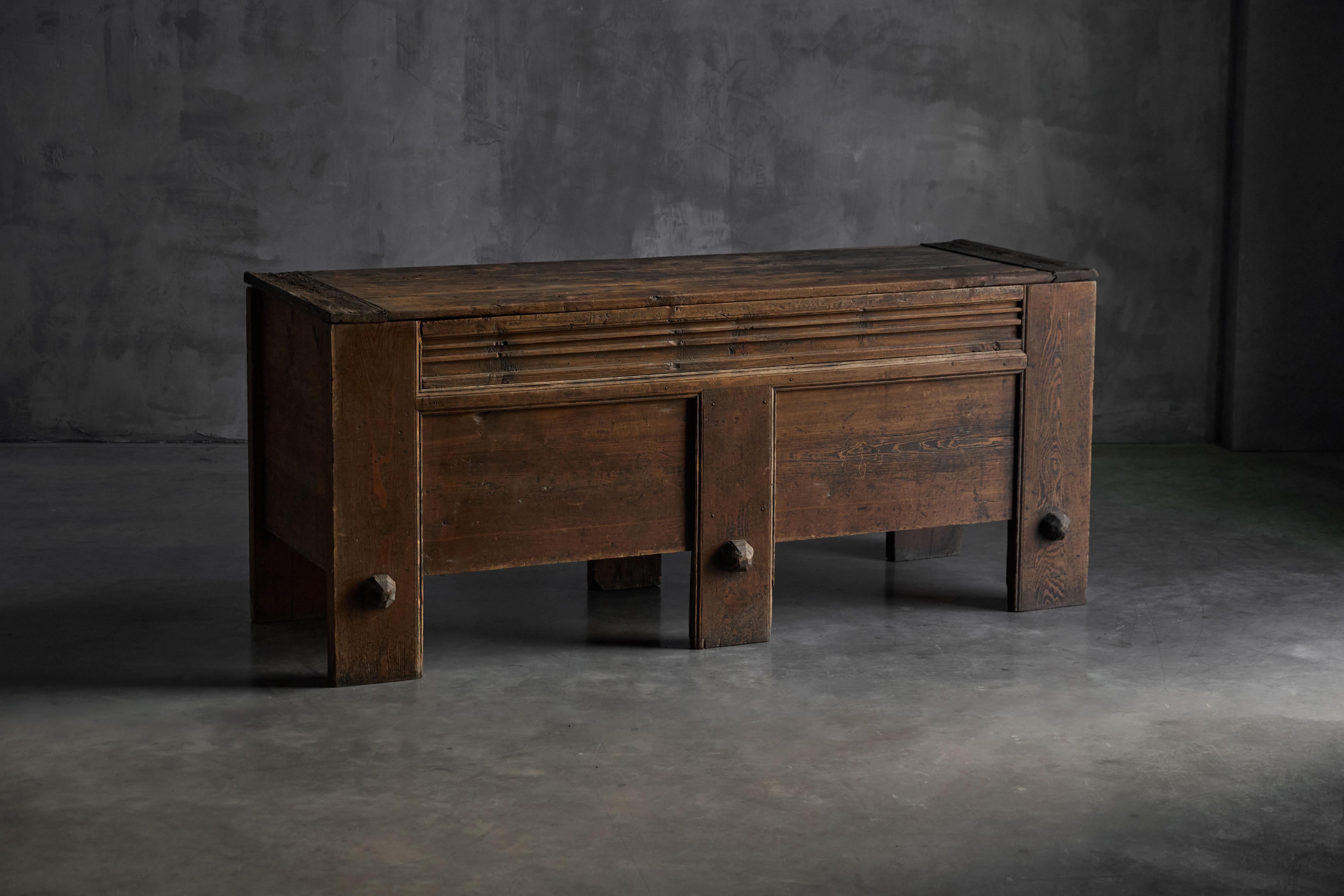 Diese alpenländische Aufbewahrungstruhe aus dem 19. Jahrhundert ist ein eindrucksvolles Beispiel für traditionelle Handwerkskunst. Die kühne geometrische Struktur wird durch übergroße, facettierte Knöpfe und tiefe, lineare Schnitzereien entlang des