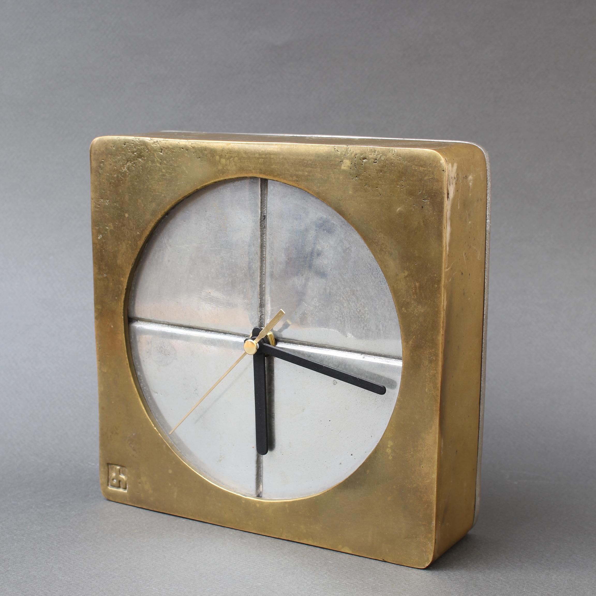 An aluminium and brass brutalist style decorative table clock by David Marshall, circa 1980s. The piece is weighty and wonderfully tactile with the maker's mark impressed on the front brass frame surrounding the clock face. The clock's original