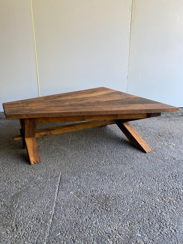 Sculptural cocktail table in the rustic Mid-Century Modern aesthetic of France and Belgium referred to as Brutalist. The heavy solid oak table is likely hand crafted and has a unique triangle shape and exposed joinery. Wax finish on scraped oak