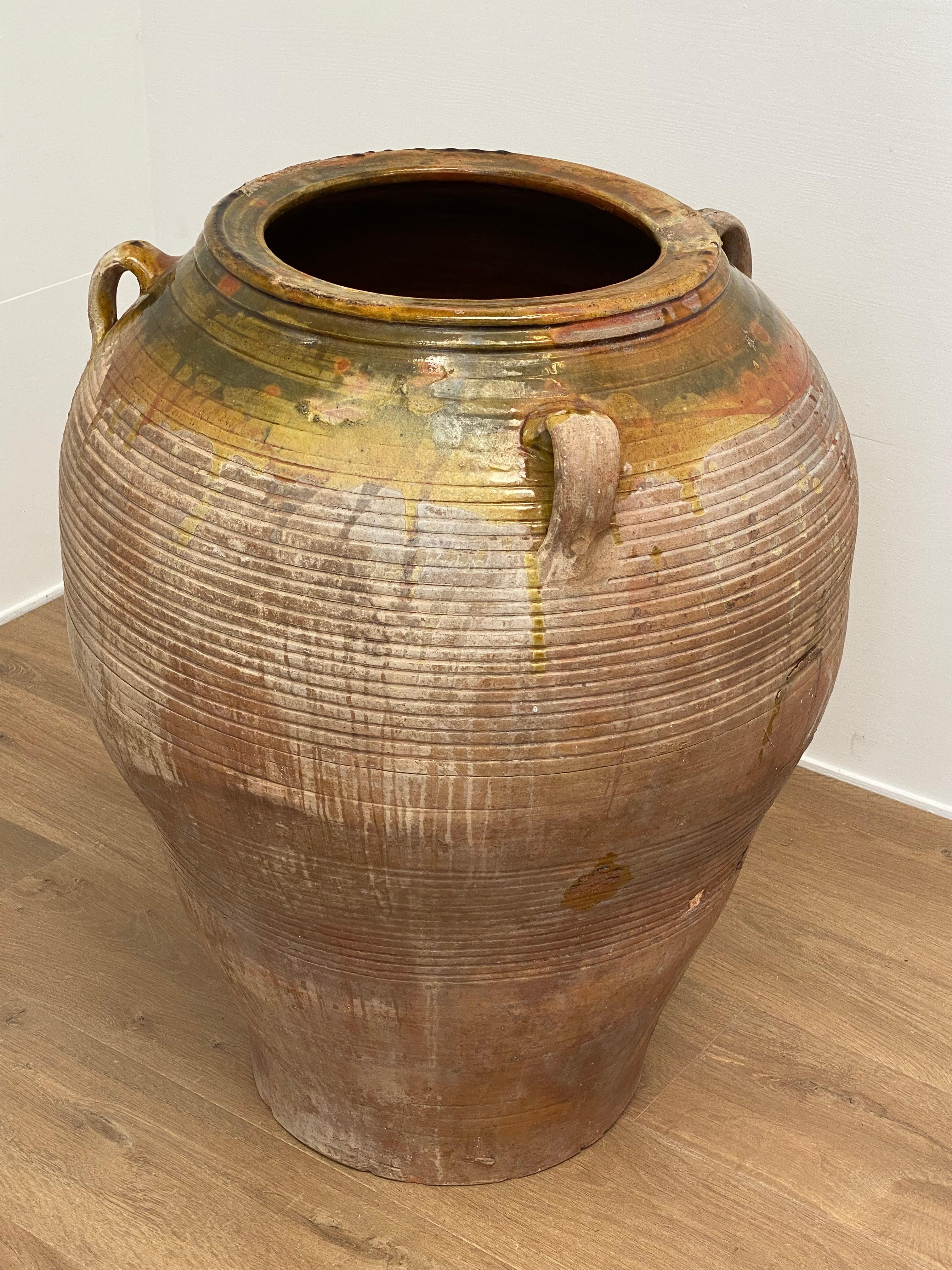 Brutalist, Antique Spanish Olive Jar from The 1930 ies,
the Jar has the classic shape and has a beautiful aged Patina,
there are 4 handles and horizontal lines as decoration,
Yellow and Green drips of glaze,
very decorative vase to be used for