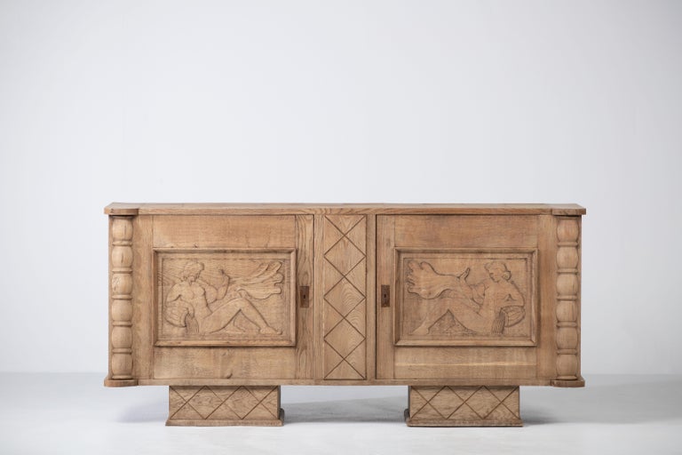 Large Art Deco Brutalist sideboard, 1940, French work. 

This unique piece consists of two doors with symmetrical carved panels featuring a hand-carved nymph on which opens a single compartment with a shelf.
The legs are covered with graphic