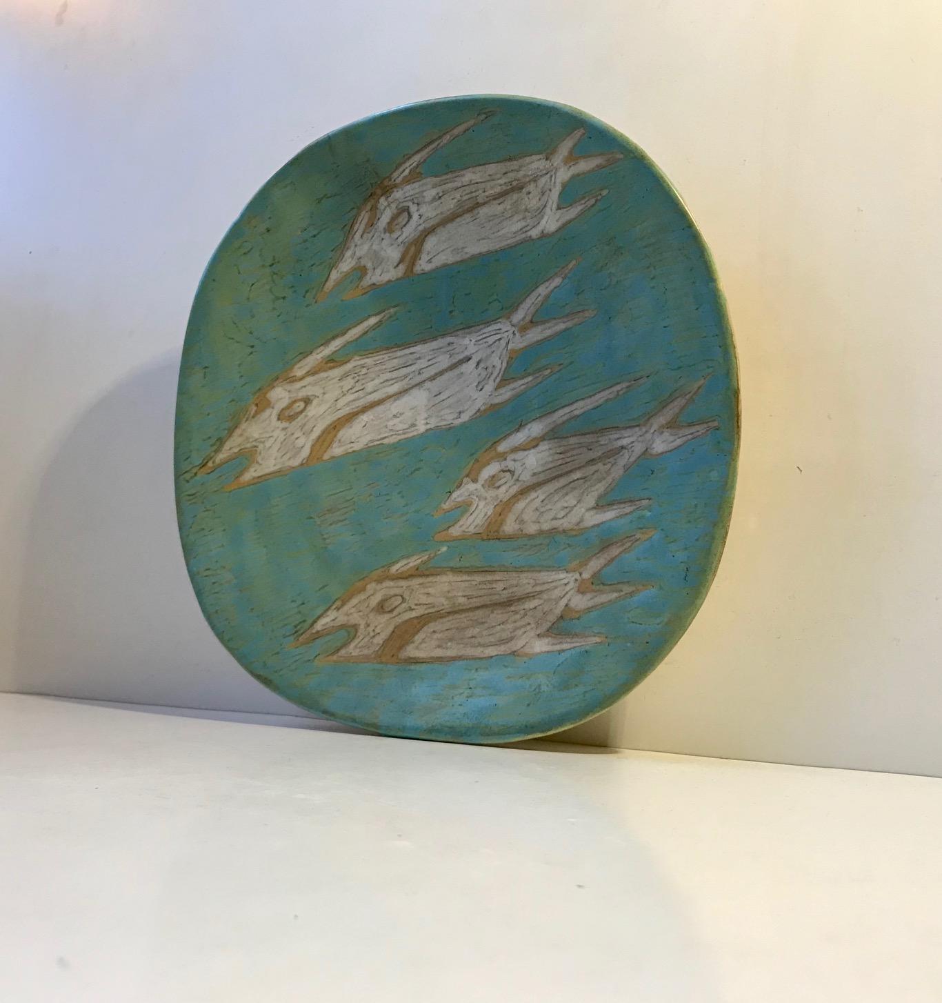 Unique art pottery dish or plaque executed by the Hungarian ceramist Gorka Livia during the 1950s. It has a deliberately crooked - asymmetrical form and has a difficult to desire main-glaze: mint, turquoise, green, blueish. Its motif depicts 4