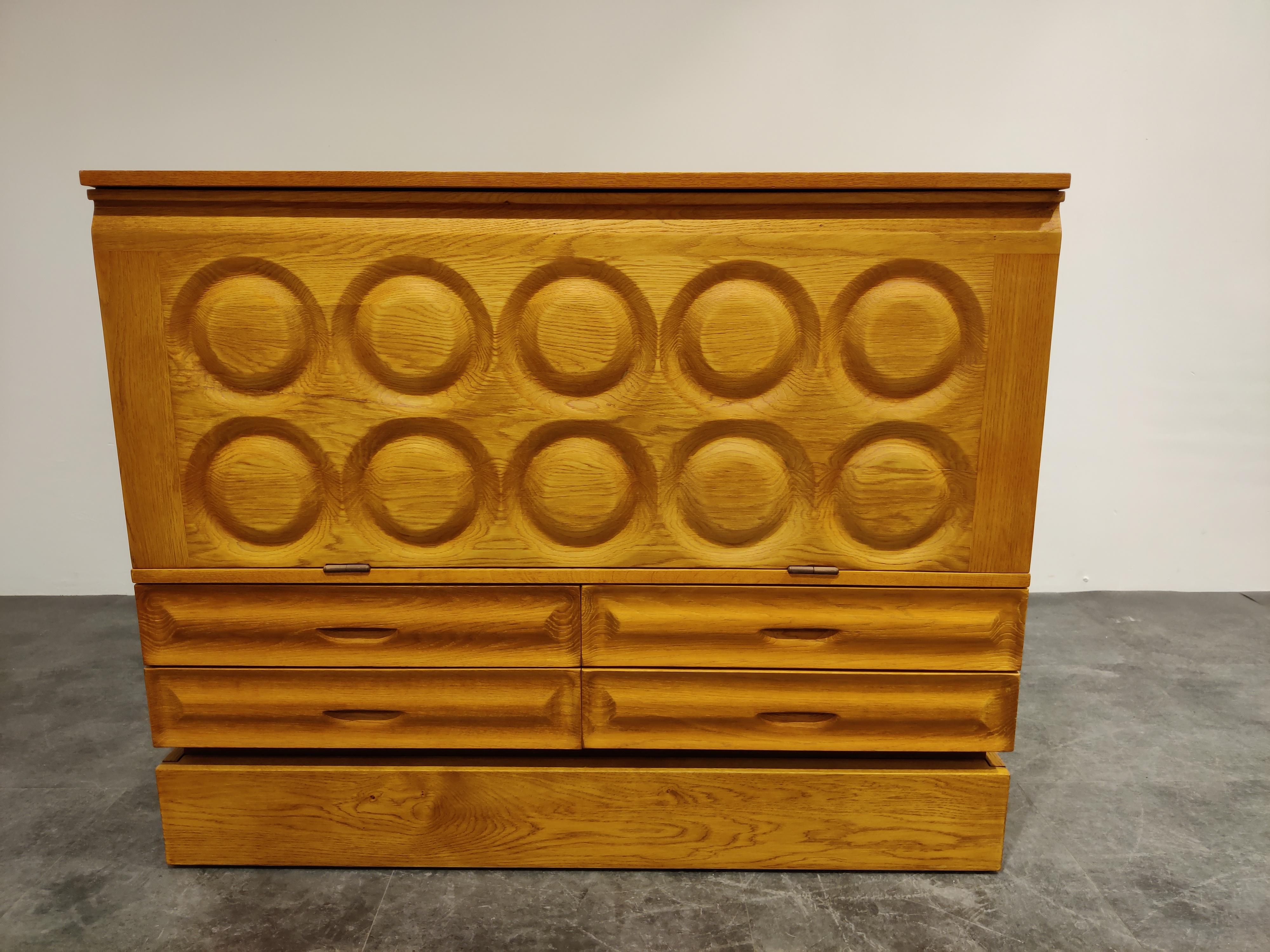 Midcentury graphical Brutalist bar cabinet with 4 drawers and a fold down door.

Beautiful timeless design in clear oak

Lovely carved handles in the drawers. 

Good condition.

1970s, Belgium

Dimensions:

Lenght 110cm/43.30