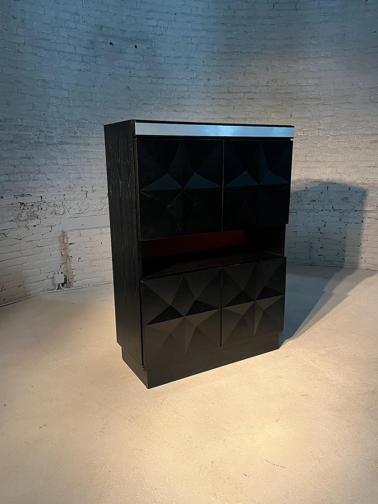 This Belgian masterpiece, attributed to De Coene in Kortrijk in the 1970s showcases an iconic diamond-shaped pattern, which gives the cabinet the typical brutalist aesthetics.

The 4 door cabinet  is spacious and stylish. Complete with a light when