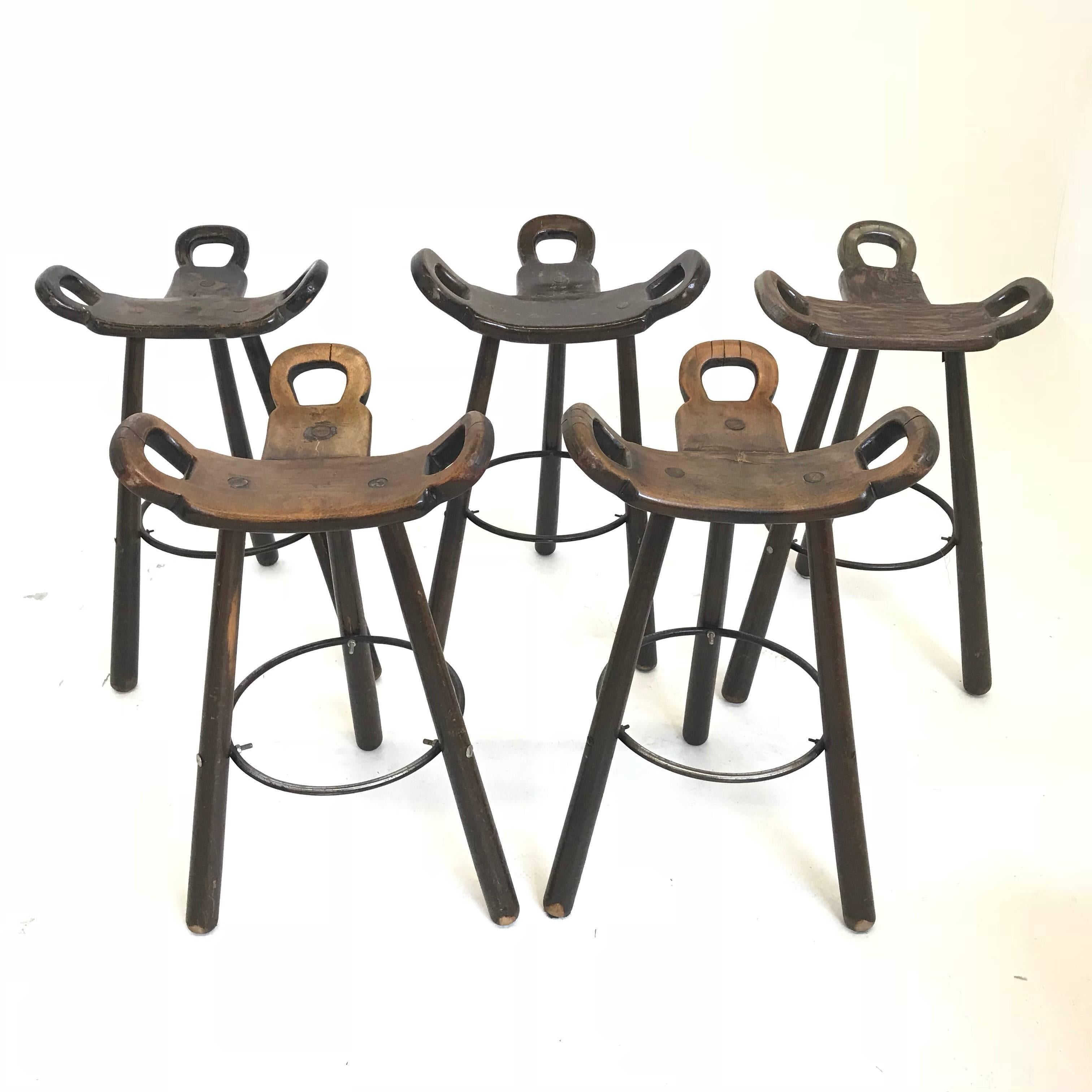 Set of five 'Brutalist' or 'Marbella' bar stools, in stained beech and metal, Spain, 1970s. A curved T-shape with three handles. The curved form makes sure the stool has a stabile seat, emphasized by the metal ring as footrest.